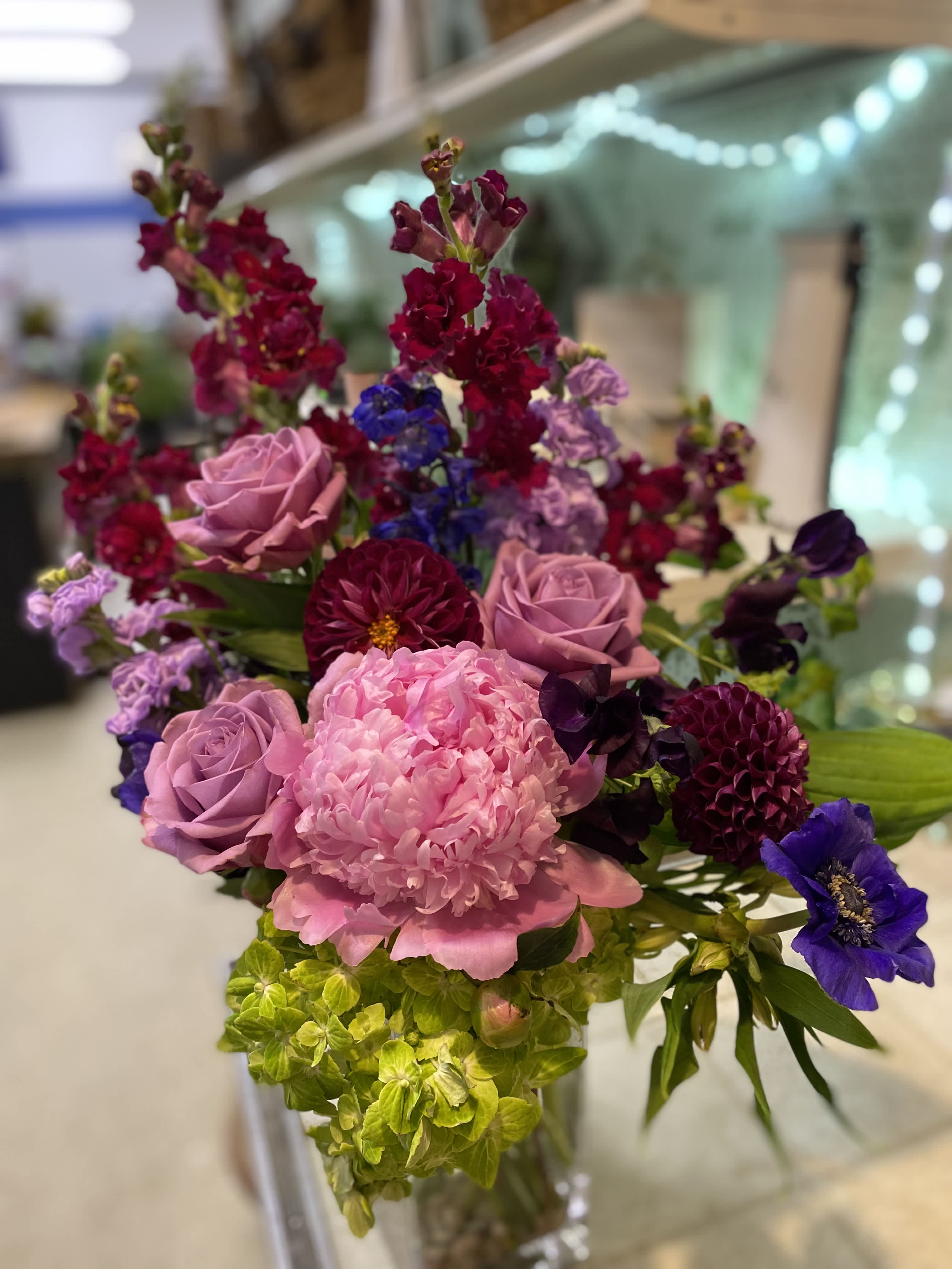Shower in pink - Tall vase arrangement with bold reds and pinks, made with snapdragons, peony, roses, and anemone. 