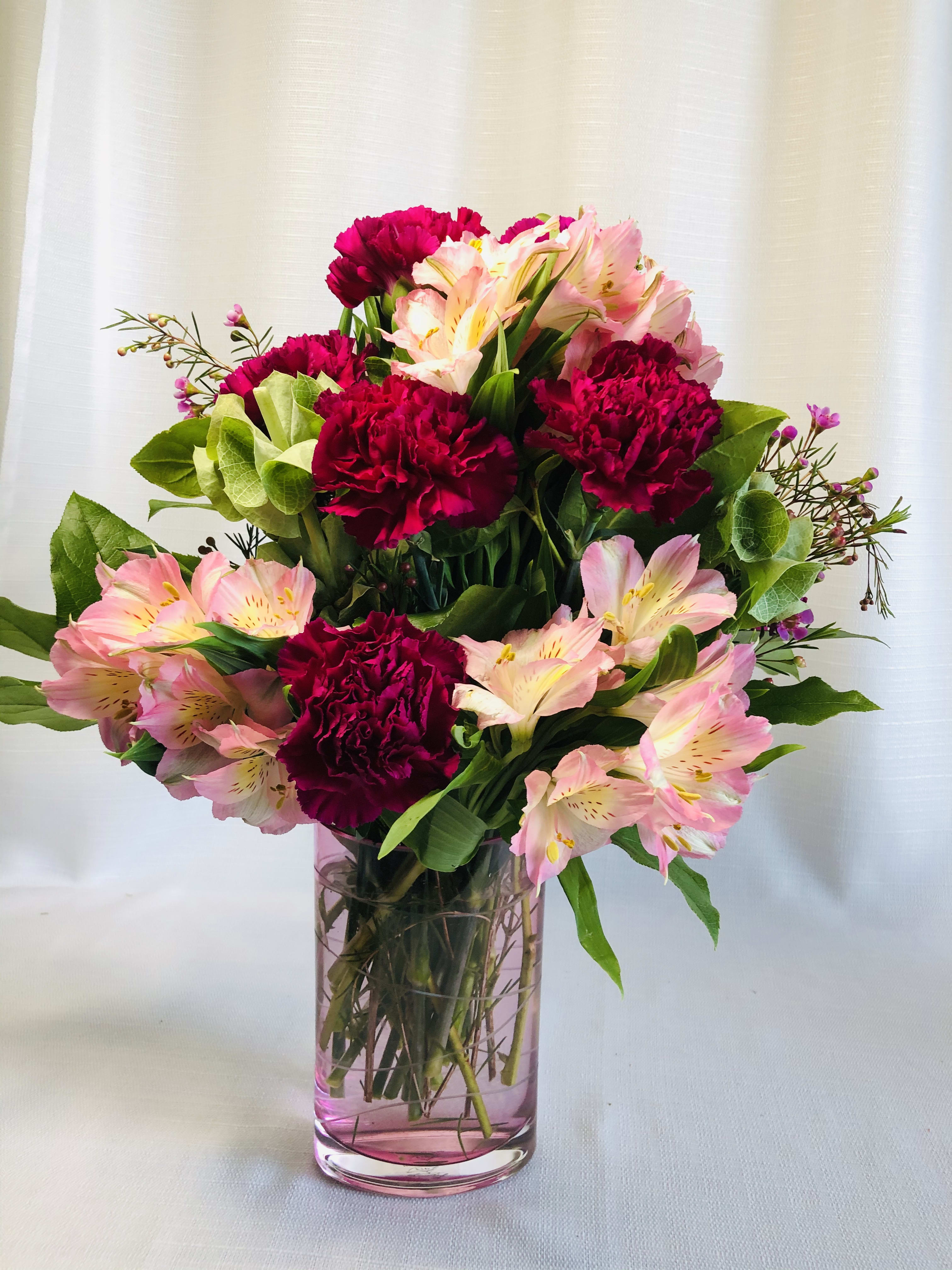 Sweet floral mix  - Lavender carnations and mix purple fillers in a beautiful pink cut glass oval vase 