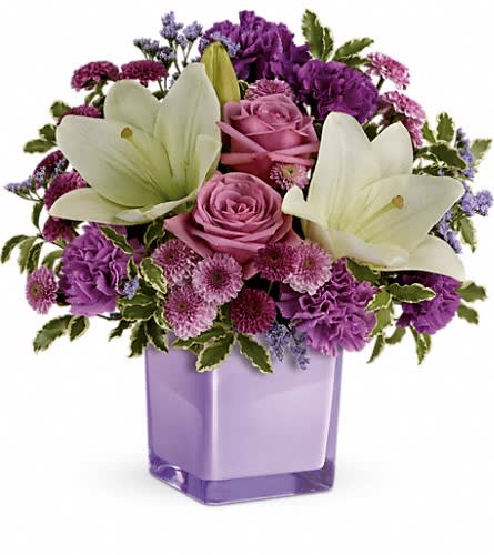 Teleflora's Pleasing Purple Bouquet - These luxurious lavender roses and crisp white lilies are poised to please! Perfectly presented in a stylish cube vase it's an any-occasion surprise they'll never forget! Lavender roses white asiatic lilies purple carnations lavender carnations purple button spray chrysanthemums and lavender button spray chrysanthemums are arranged with lavender limonium and pitta negra. Delivered in a glass cube.Approximately 13 1/2&quot; W x 13 3/4&quot; H Orientation: One-Sided As Shown : TEV45-1ADeluxe : TEV45-1BPremium : TEV45-1C
