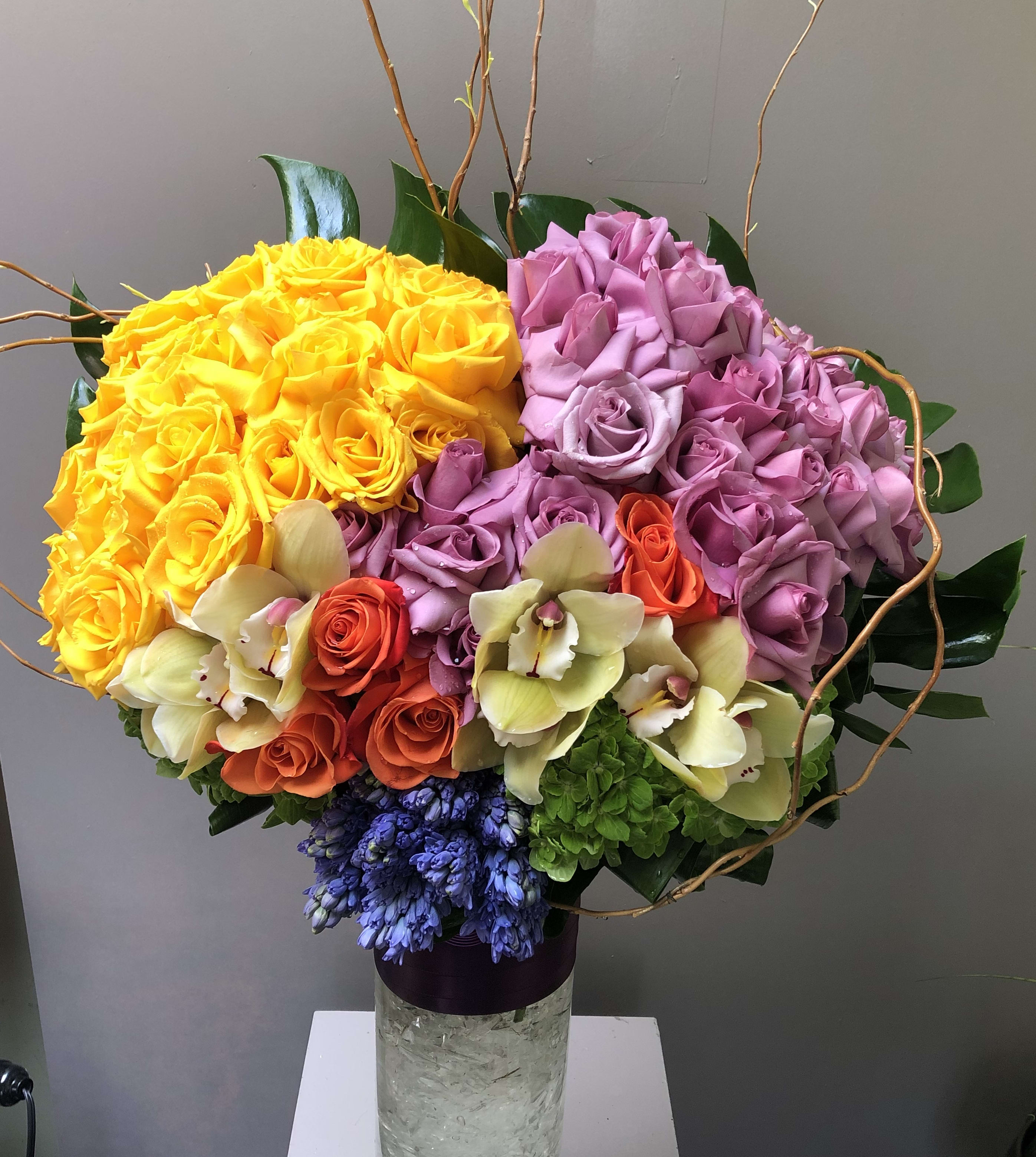 Strong Mixed #EF14 - Grand Colorful Arrangement about 2 dz yellow 2 dz lavender a few orange roses put together with monstera leafs in the back blue hyacinths and orchids in front very cheerful &amp; hapy