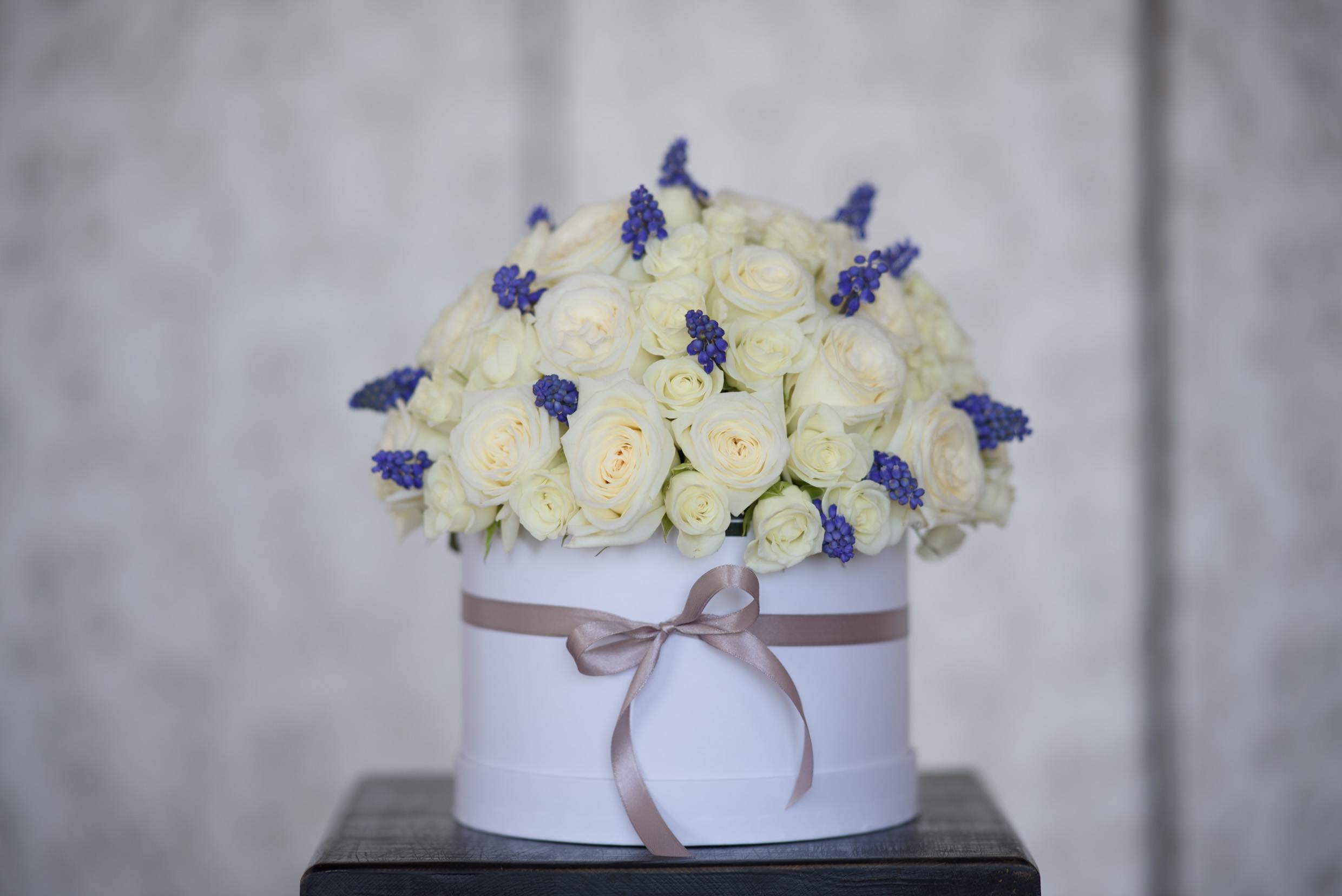 Fiona - The Fiona arrangement delivery includes: Premium, equadorian white roses (up to 30 - medium sized box, up to 50 - large sized box) accented with bursts of purple statice  (Color may vary) Care instructions Your custom message on our Luxe stationary Hat box size: Medium - D8.5H4.5', Large - D10H6'.