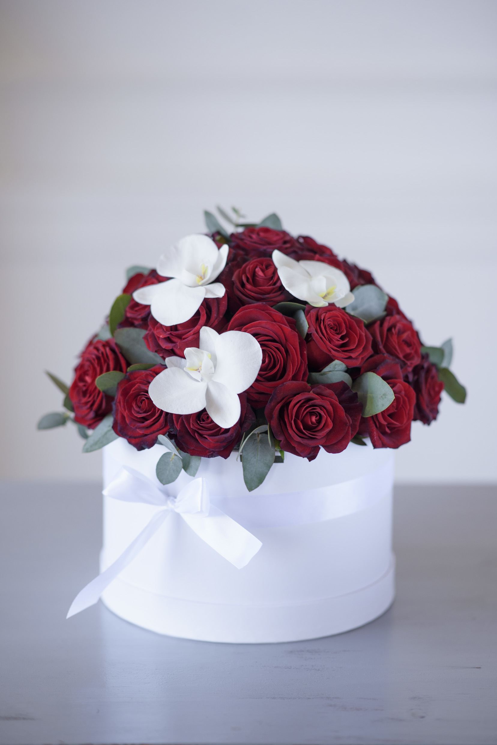 Margaret - Premium, equadorian red roses (up to 30 - medium sized box, up to 50 - large sized box) accented with fresh cut orchids  (Color may vary) Care instructions Your custom message on our Luxe stationary Hat box size: Medium - D8.5H4.5', Large - D10H6'.