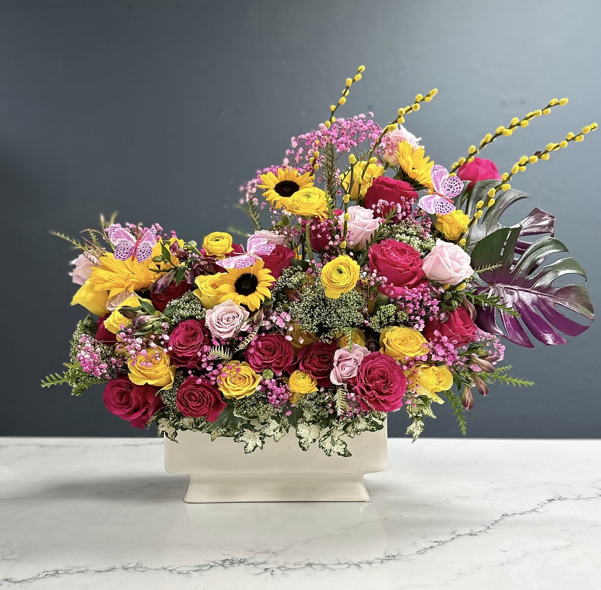 Luminosité - A vibrant masterpiece designed elegantly with a mixture of the finest fresh cut roses, seated on a white rectangular ceramic vase.