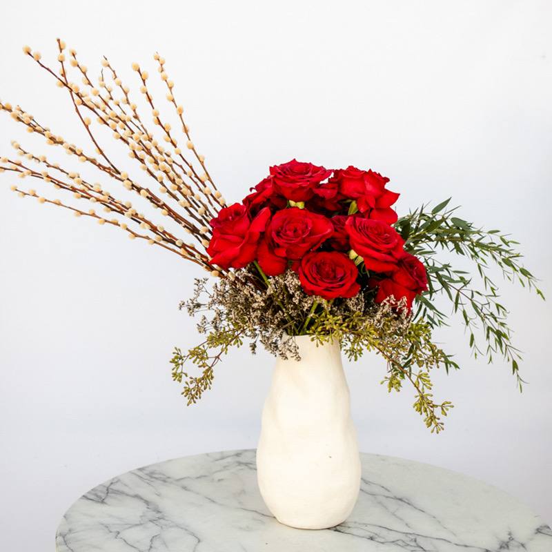 Cherry Rose - Our &quot;Cherry Rose&quot; bouquet is a symphony of elegance and passion, where each meticulously selected red rose stands tall and proud, radiating an aura of timeless beauty. This arrangement that’s artfully presented in a cherished white vase is a statement piece worthy of the most sophisticated taste.  Approximately 21” W x 18” H
