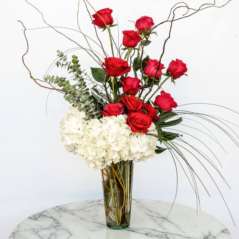 Classical Rose - In a world consistently on a rush towards the future, our “Classical Rose” floral arrangements will always be a classic! This is our take on the nostalgia of flowers’ aesthetics of yesteryears designed for those who find solace in the familiarity of tradition. Timeless bouquets to serve as a reminder that some things never fade and the beauty of the past can be seamlessly woven into the fabric of the present.    Roses are available in a spectrum of hues. For any color preference other than red, please specify in the “Special Instructions” at checkout.  Approximately 26” H x 16” W