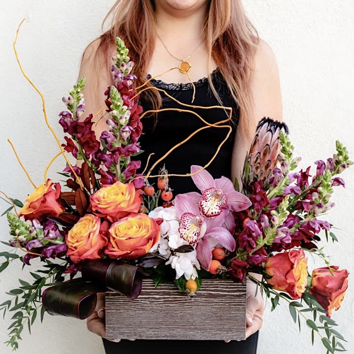 Autumn Harmony - Behold the rich tapestry of the season’s hues in this “Autumn Harmony” arrangement! Shades of orange, red, and purple dance harmoniously in a glass vase with each bloom telling a story of fall's warmth and beauty. A truly breathtaking bouquet!  Approximately 16” W x 14” H