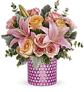 Pink Breeze - Like a fresh spring breeze, this light pink and peach bouquet will lift their spirits and refresh their day! The lovely arrangement of roses and lilies is presented to perfection in a delightful pink glass vase with debossed dots and glamorous metallic finish.