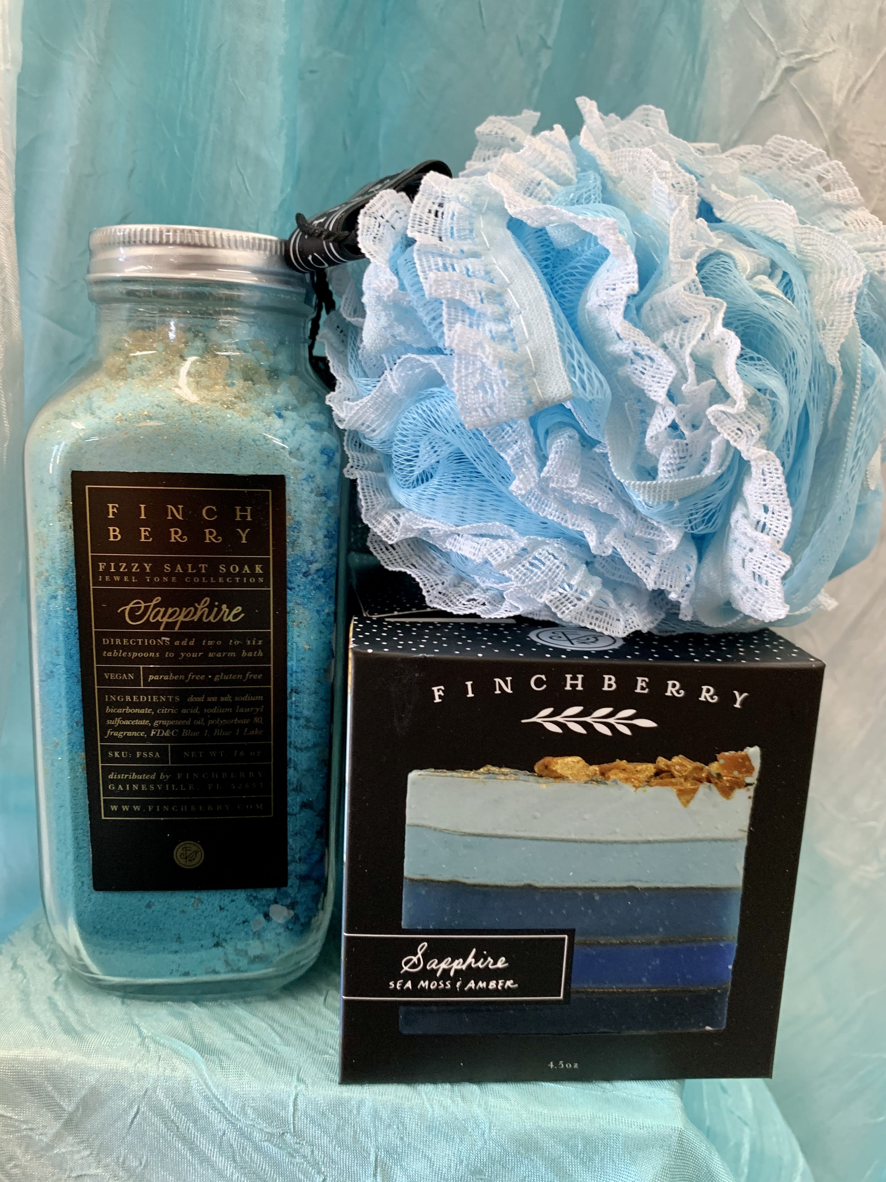 Sapphire gift set - Finchberry - Sapphire harnesses the exhilaration of a coastal sea spray infused with the rich scent of warm amber to craft the tranquil moment you deserve. This scent transcends your traditional cleaning routine and allows the cascading blue colors of the soap to provide the ultimate self-care experience. This gift set includes Fizzy Salt Soak, Bar soap, and Loofah Sponge.