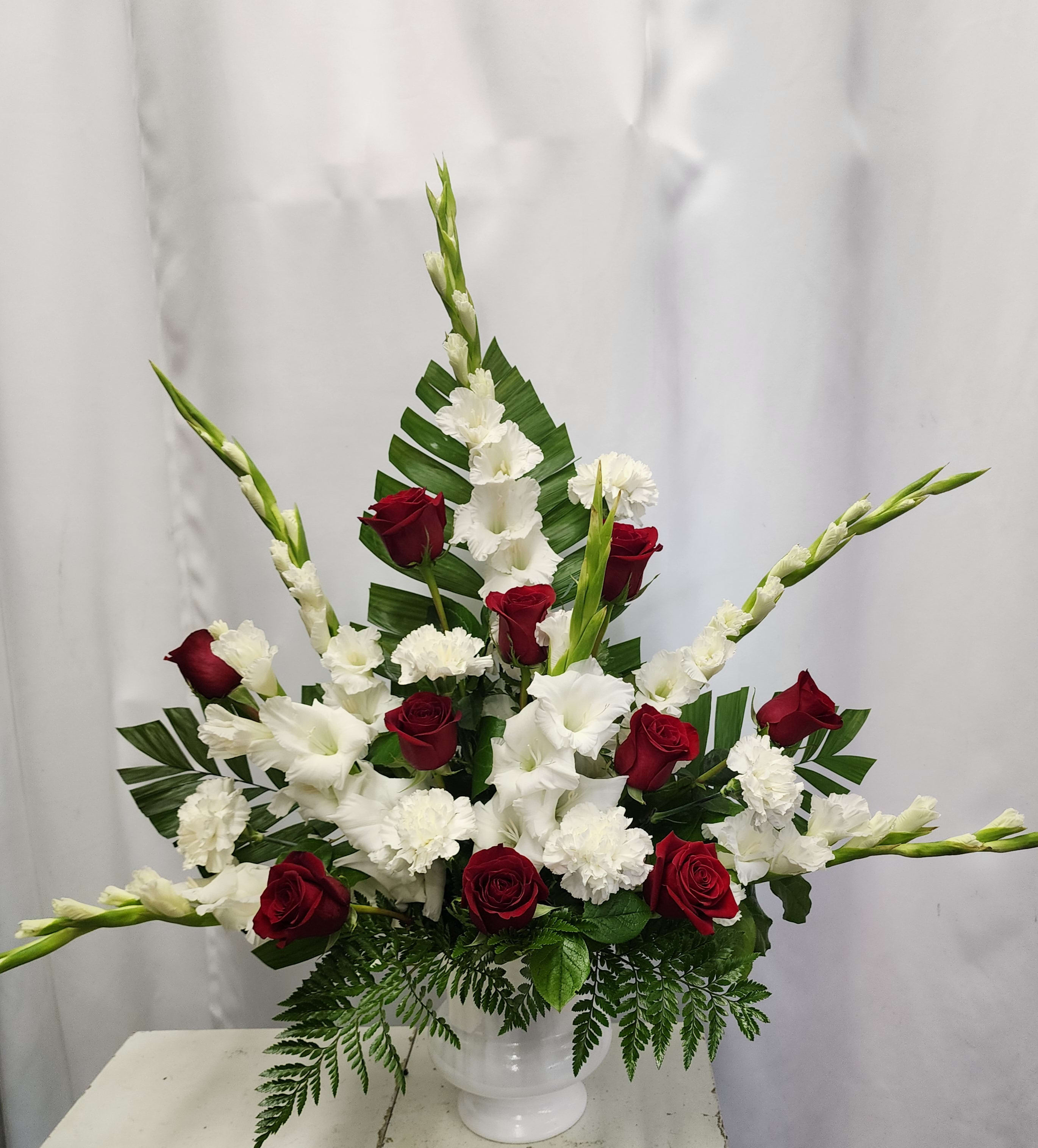 Red &amp; White Classic Tribute - A beautiful presentation of Red Roses and Whites Carnations and Gladiolas creating a wonderful sympathy arrangement. Colors can be modified if desired. Please leave color preferences in notes to florist. 
