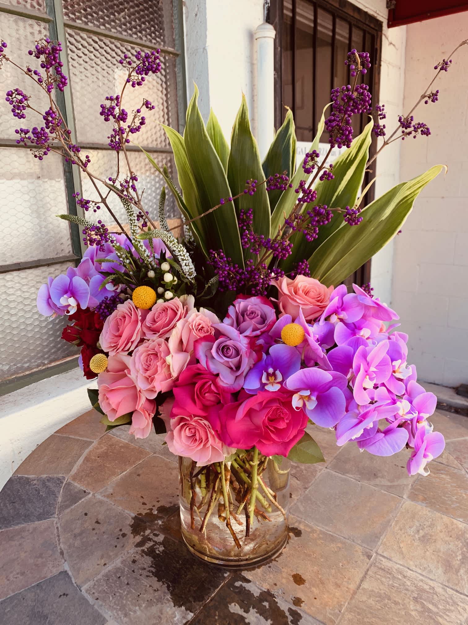Beverly Hills Lush - This is beautiful 8x12 clear vase with green large leaves with blossom willow and large orchids. Comes with large roses and mix garden flowers. 