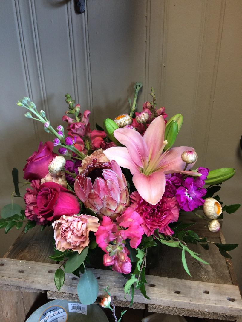 Raspberry Ripple Custom Designed Bouquet by Cold Spring Floral - Raspberry Ripple will Brighten any Space in your Home or Office. A bright Modern Bouquet with Protea, Hot Pink Snapdragons, Stock, Hot Pink Roses, Pink Asiatic Lily with Blush Carnations and Mixed Greenery all arranged in a low Cube Vase. Protea flowers are a SPECAIL ORDER ONLY, so keep in mind when ordering this we need a 2-3 BUSINESS DAY NOTICE to order them in special for your bouquet. Some substitutions may apply depending on availability of the flowers. 