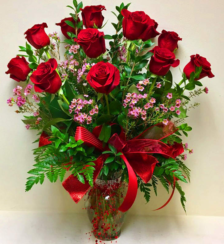 Classic Dozen Roses - Express your affection with a classic symbol of love. One dozen long stem premium roses beautifully arranged in a clear tall vase with seasonal greenery. Deluxe size is with 2 Dozen roses. Rose color choices available are red, white, pink, purple, and yellow . (Please specify color choice in the special instructions)