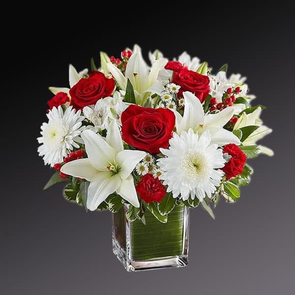 Manifestations of love - Add some romance to the holiday season with this rich arrangement of luxurious flowers in classic winter colors. Red roses, snow white lilies and playful daisies are gathered in our ruby a glass cube.