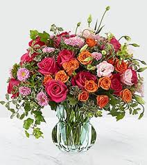 The Queen's Garden The Queen's Garden - When only the best will do, this fresh flower arrangement delivers. A collection of colors and textures that keeps the eye dancing from one point to the next, this artisan floral design blends hot pink roses with orange spray roses, pink double lisianthus, pink Veronica, pink matsumoto asters, and orange protea with the lush green foliage of ivy vines, variegated pittosporum, and trend forward design. *Vase may vary