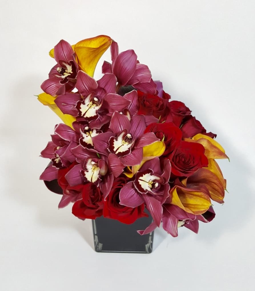 Mary Sanderson - Modern arrangement of fresh red roses, Cymbidium Orchids, and Calla Lilies in a clear vase.   Approximately 11&quot; H by 8&quot; W