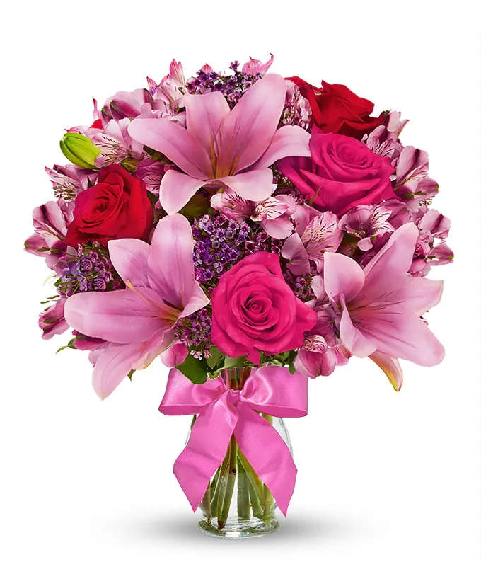 Valentine's Day Pink lily and Hot Pink Rose bouquet - Send stunning flowers to celebrate any occasion! With classic floral colors including red roses and pink lilies, the Rose and Lily Celebration is a wonderful gift to send to a friend or family member for a birthday, get well or anniversary. The flowers are arranged by hand at a local florist shop. The floral artist creates the Rose and Lily bouquet with red roses, pink roses, pink lilies, pink alstroemeria and purple waxflower. Paired with the flowers is a keepsake clear vase that is wrapped in a decorative ribbon. Measures 14&quot;H by 12&quot;L.  Includes: • Pink Asiatic Lilies • Pink and Red Roses • Purple Waxflowers • Alstroemeria • Glass Vase