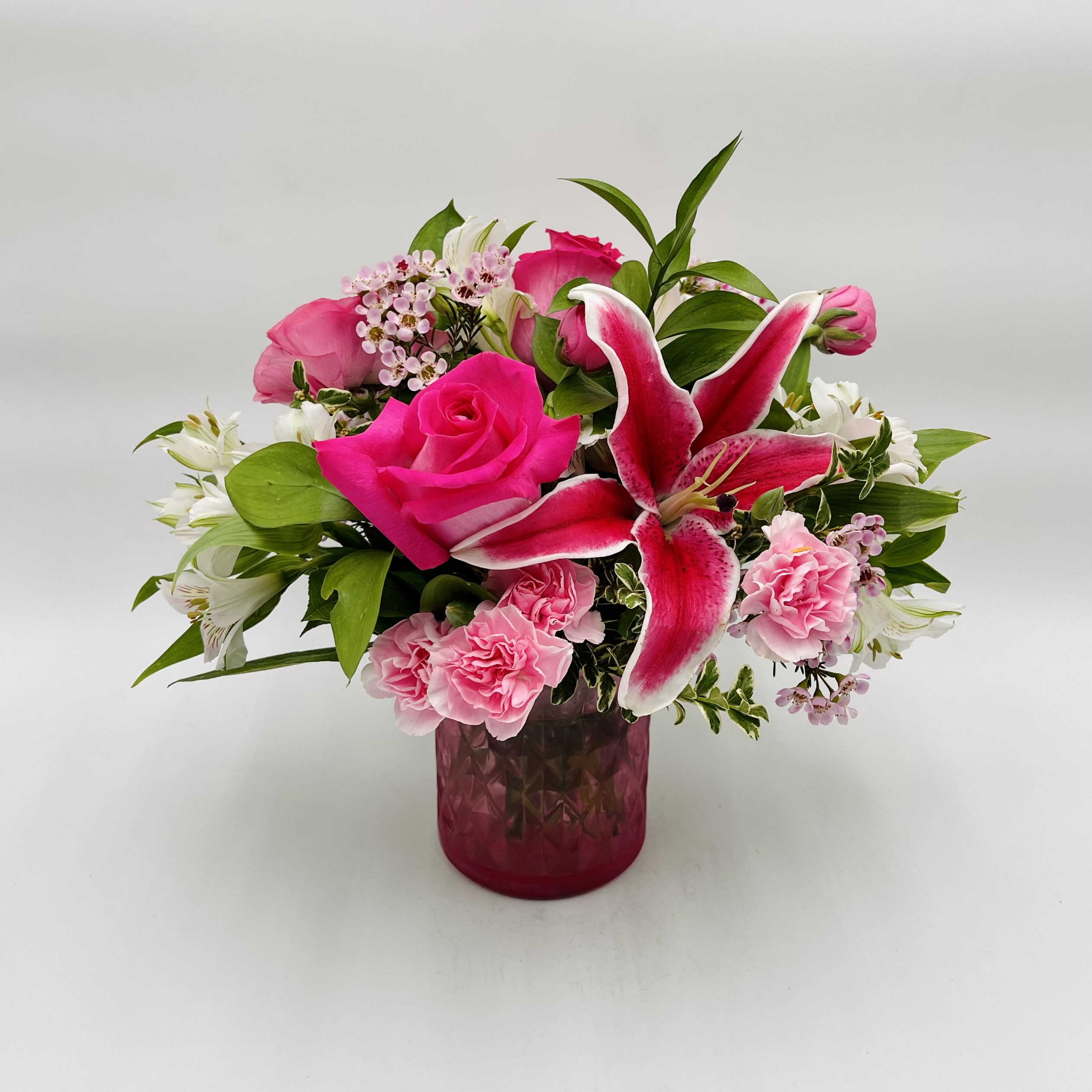 Pink Diamond Mother’s Day Bouquet - A beautiful arrangement of pink blooms in a diamond cut glass vase. Perfect for Mother’s Day.  Arrangement includes stargazer lilies, pink roses, carnations, waxflowers, and alstromeria, accented with assorted greenery.