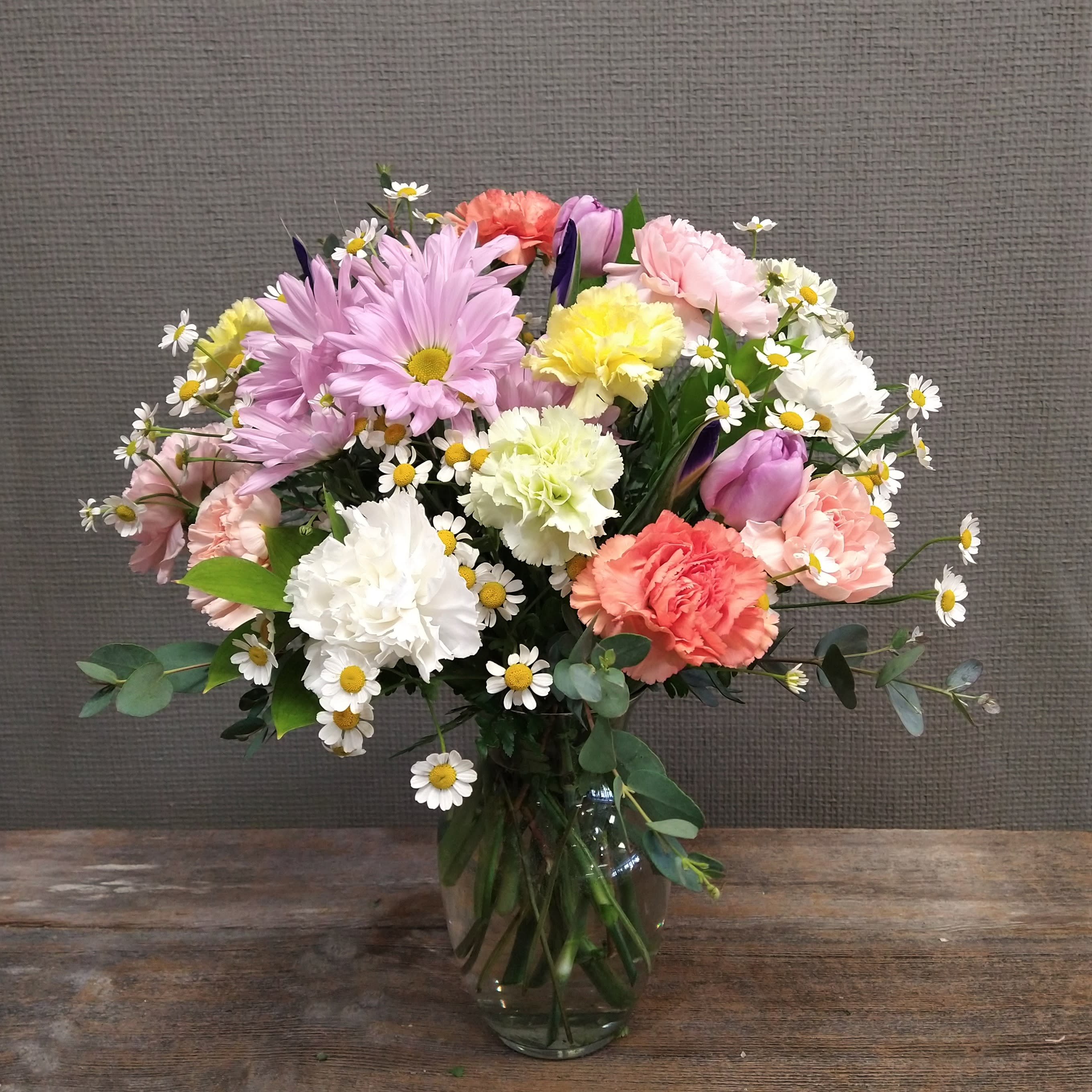 Spring is All Around - Spring has sprung! This pastel rainbow has carnations, tulips, and iris that gives a fun, uplifting boost for any occasion.