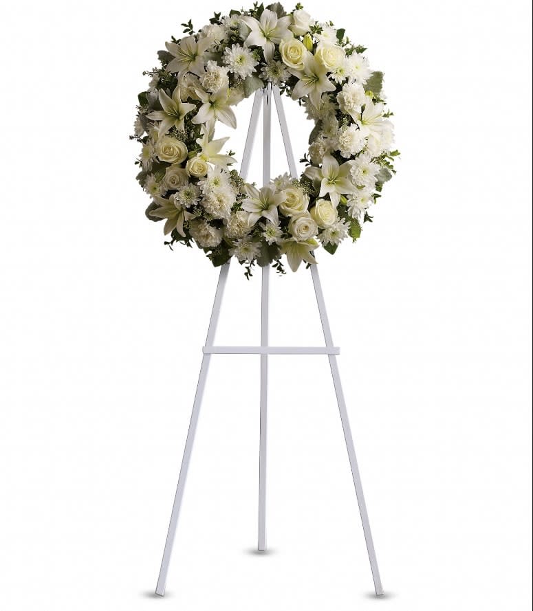 Serenity Wreath - A ring of fragrant, bright white blossoms will create a serene display at any funeral or wake. This classic wreath is delivered on an easel, and is a thoughtful expression of sympathy and admiration. A standing wreath created from fresh white flowers such as roses, Asiatic lilies, carnations and cushion spray chrysanthemums - accented with greenery - is delivered on an easel. Approximately 22&quot; W x 22&quot; H 