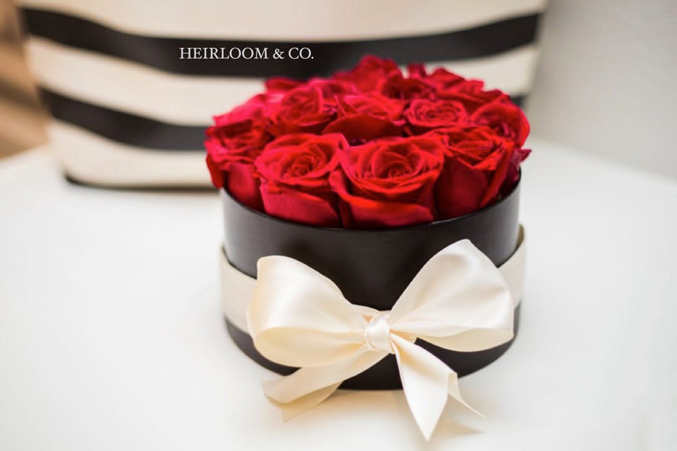 Miss Monroe  - A DOZEN PREMIUM RED ROSES, LUXURY MATTE BLACK HATBOX, AND THE PERFECT SATIN BOW TO TIE IT ALL TOGETHER  1950’s vintage glamour mixed with a modern, yet timeless pop of red, this signature arrangement was inspired by the iconic Marilyn Monroe. Charming, stylish, and elegant, with a hint of scandal, this arrangement is perfectly emblematic of the era’s attitudes towards love and lust.   Consisting of a dozen hand selected red roses, presented in a black matte hat box, and tied together with the perfect satin bow, it is sure to mesmerize, just as Ms. Monroe herself did each time she walked into a room.