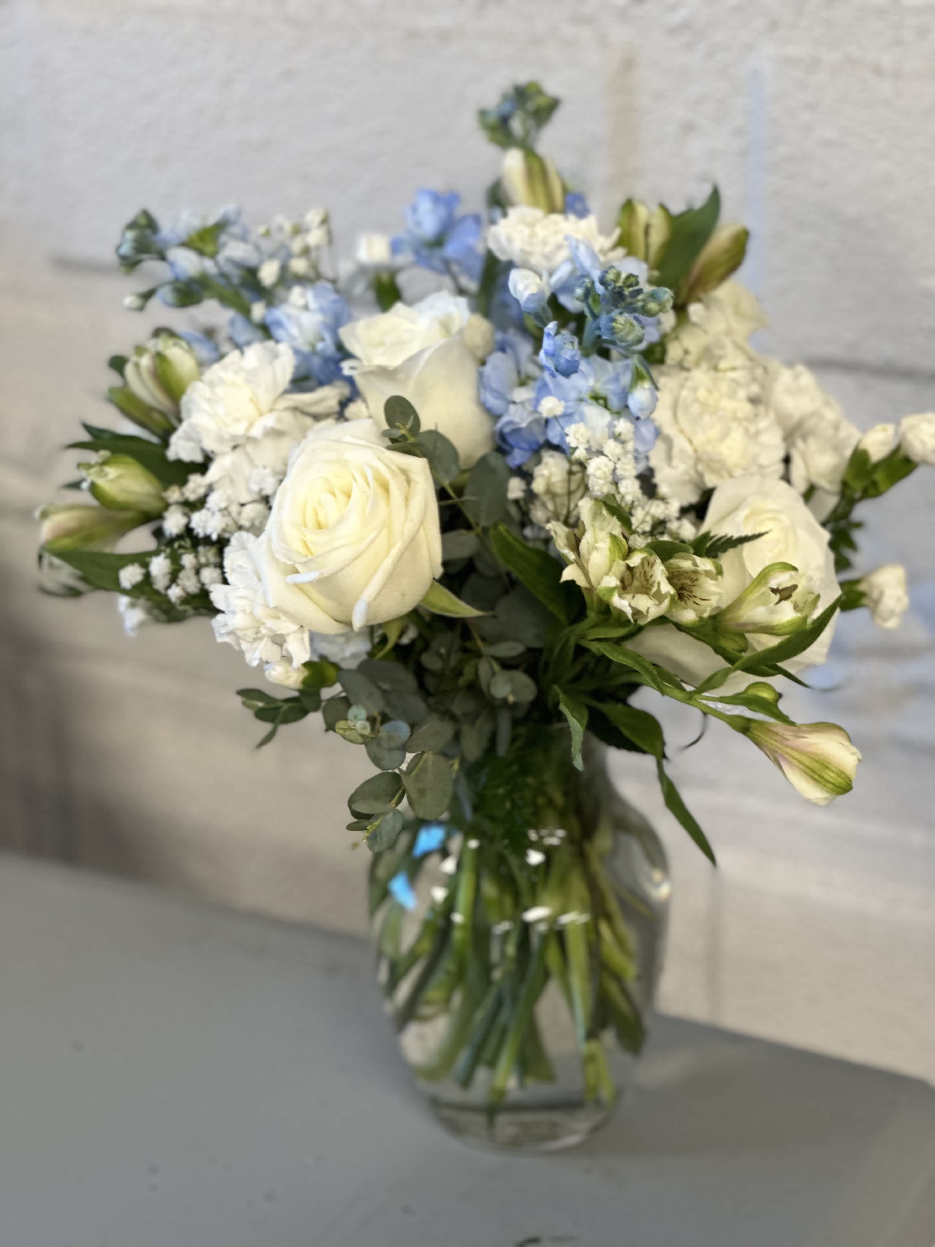 Gentle Reflections - This vase arrangement is adorned with a harmonious blend of delicate roses, vibrant carnations, and fragrant stock flowers, accented with subtle powder blue accents.