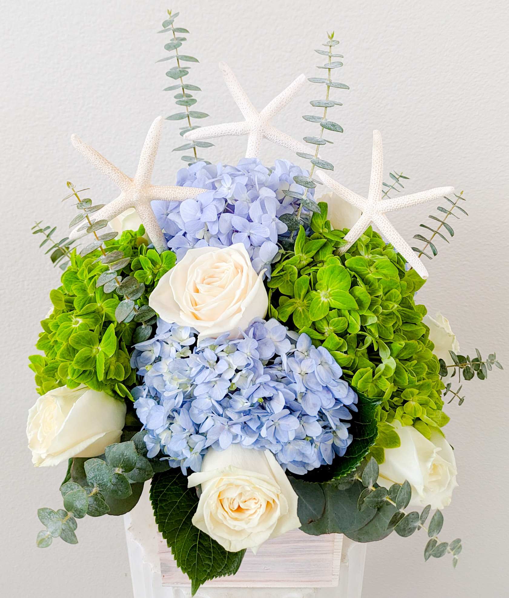 Seaside - 6&quot; x 6&quot; wood box filled with white roses, blue hydrangeas, green hydrangeas, and starfish accents.