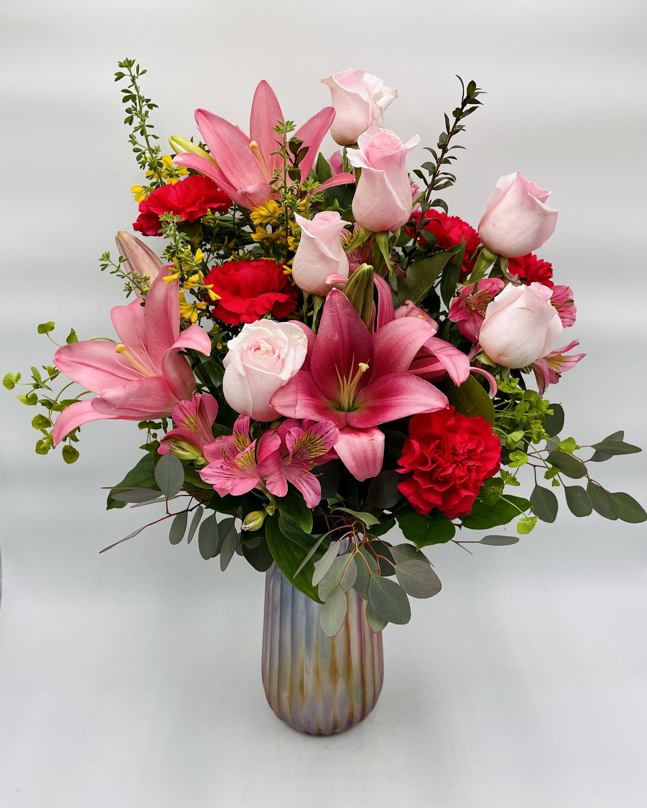 Iridescent Bouquet - Mother's Day - Mom will adore this gorgeous bouquet featuring pink roses and blooms overflowing from a luxurious, iridescent vase.  Arrangement includes pink roses, lilies, alstromeria, red carnations, and assorted greenery in a pink iridescent vase.  