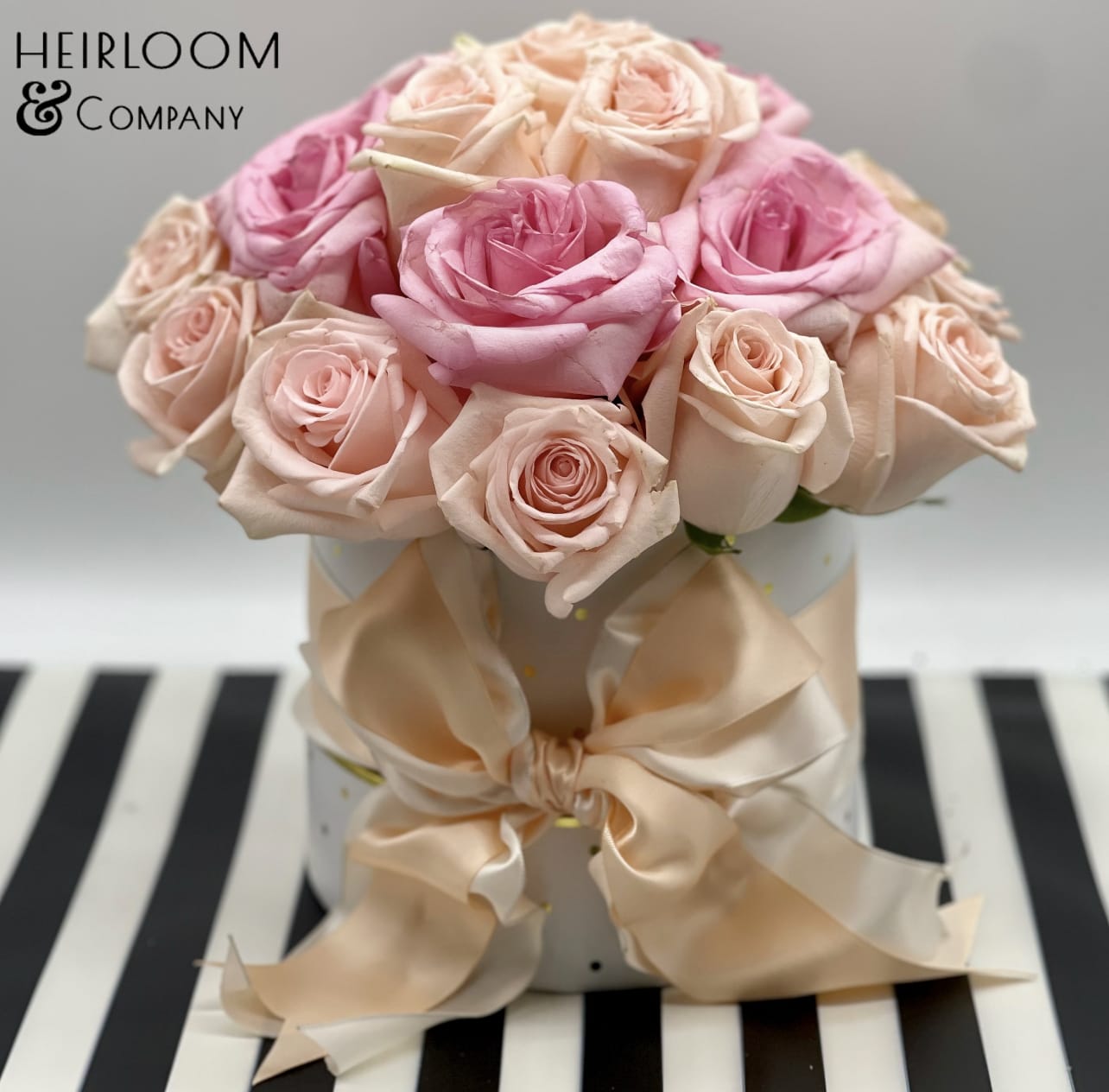 Stassy Stassy - This adorable Arrangement is presented in a white hat box with gold shimmer polkadots, and wrapped with a double layer peach and ivory fluffy satin bow. It is filled with almost premium hand-picked blush and pink garden-variety roses.