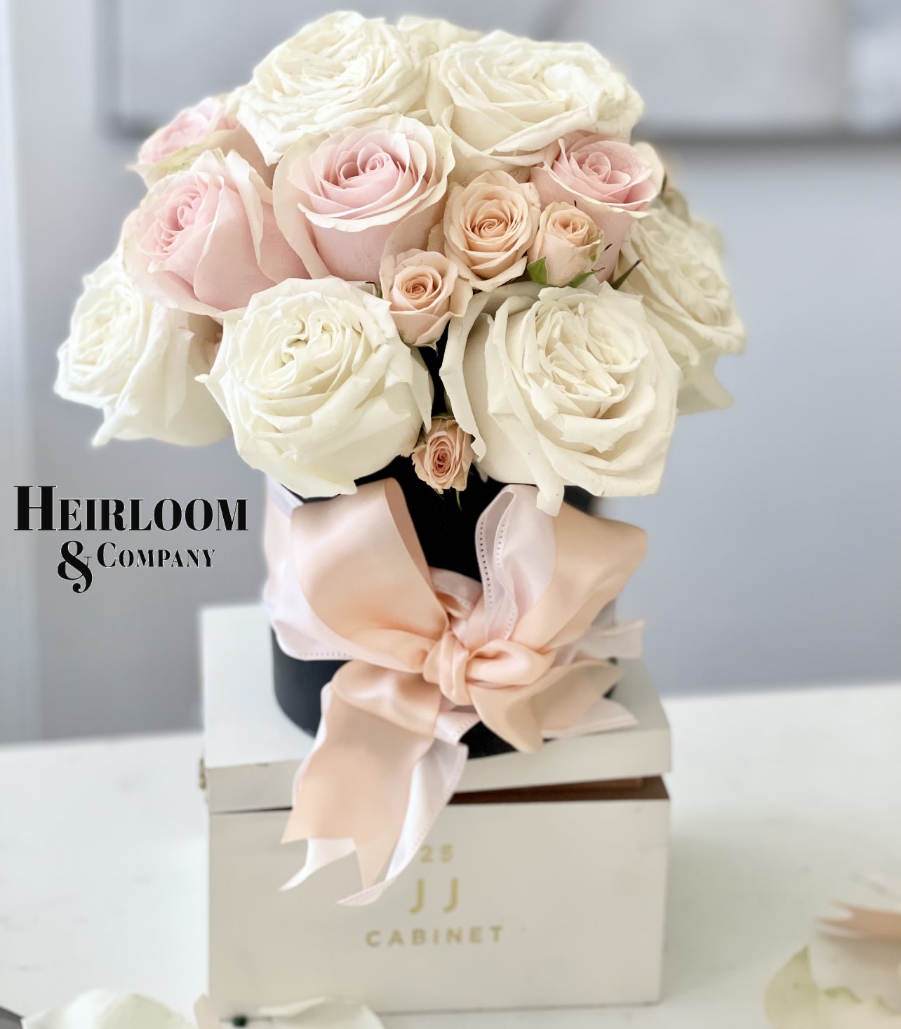 Happy Valentines Day, Darling! Flower Arrangement - A delightful burst of joy to brighten any day! This charming bouquet features a harmonious blend of white garden roses, blush roses, and peach spray roses, elegantly nestled in a matte hatbox inspired by the romance of France. Tied with a double-layer satin ribbon in the soft hues of blush and peach, this arrangement is a perfect way to express your love and warm wishes. Surprise someone special with this sweet and sophisticated floral gift that's as beautiful as they are. Order now and let the celebration bloom!&quot;