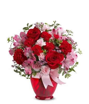 Simply Love - Let the whole world know how much she means to you with a delivery of the Blissfully Yours bouquet. The flower bouquet is arranged with a mix of different flower types all in either pink or red tones. The stand-out flower is the red rose which is paired by a local florist near the delivery address with pink alstroemeria, red carnations and pink wax flower. The roses, carnations and alstroemeria are delivered by hand in a bright red vase, wrapped with a pink bow.   Includes:  • Red Roses  • Pink Alstroemeria  • Red Carnations  • Pink Waxflower  • Red Vase with Ribbon