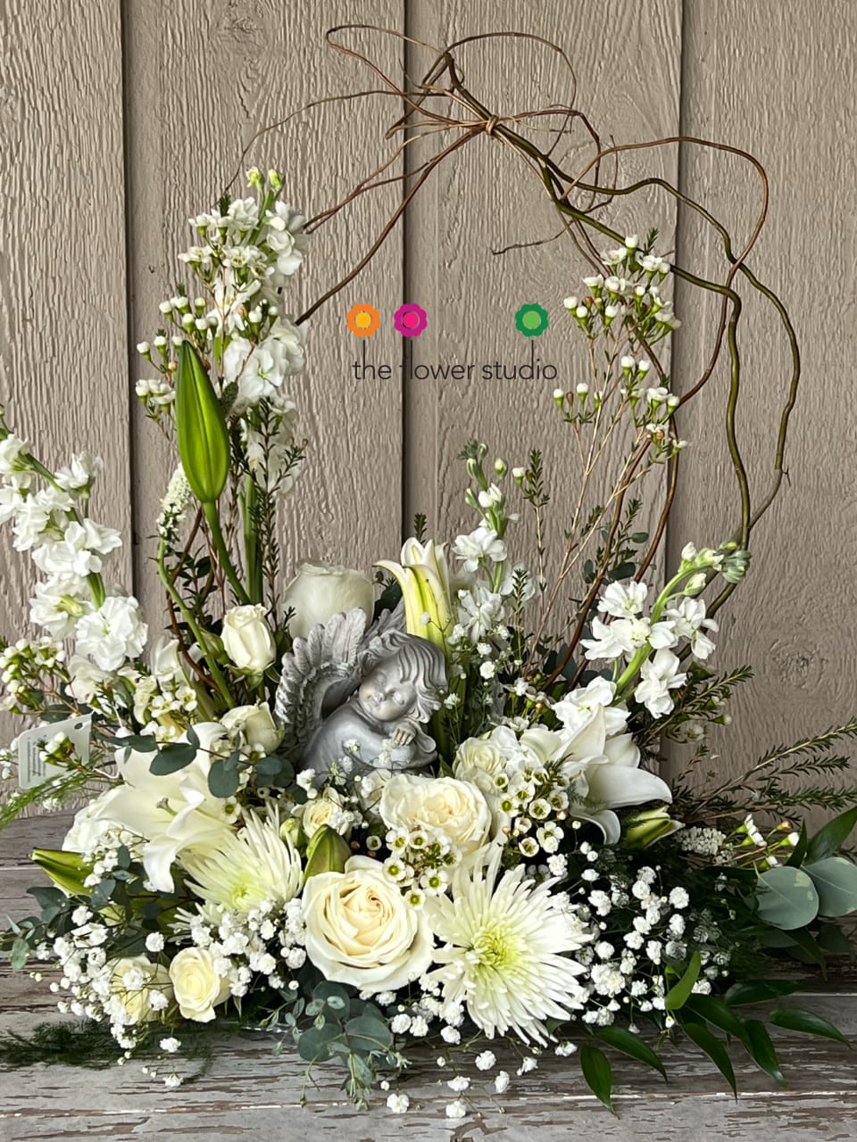 Guiding Angel Bouquet - As serene as gently falling snow, this pure white arrangement of roses, lilies and stock is a heartfelt symbol of peace and beauty. Its graceful angel keepsake sculpture will remain a guiding light to your loved ones for years to come. White roses, white cushions, gyp, white stock, white lilies are arranged in a Lomey dish making the focal area, the Guardian Angel. Contents/ Angel may vary - if any specific flowers/colors, please let us know. We will try our best to accommodate. 