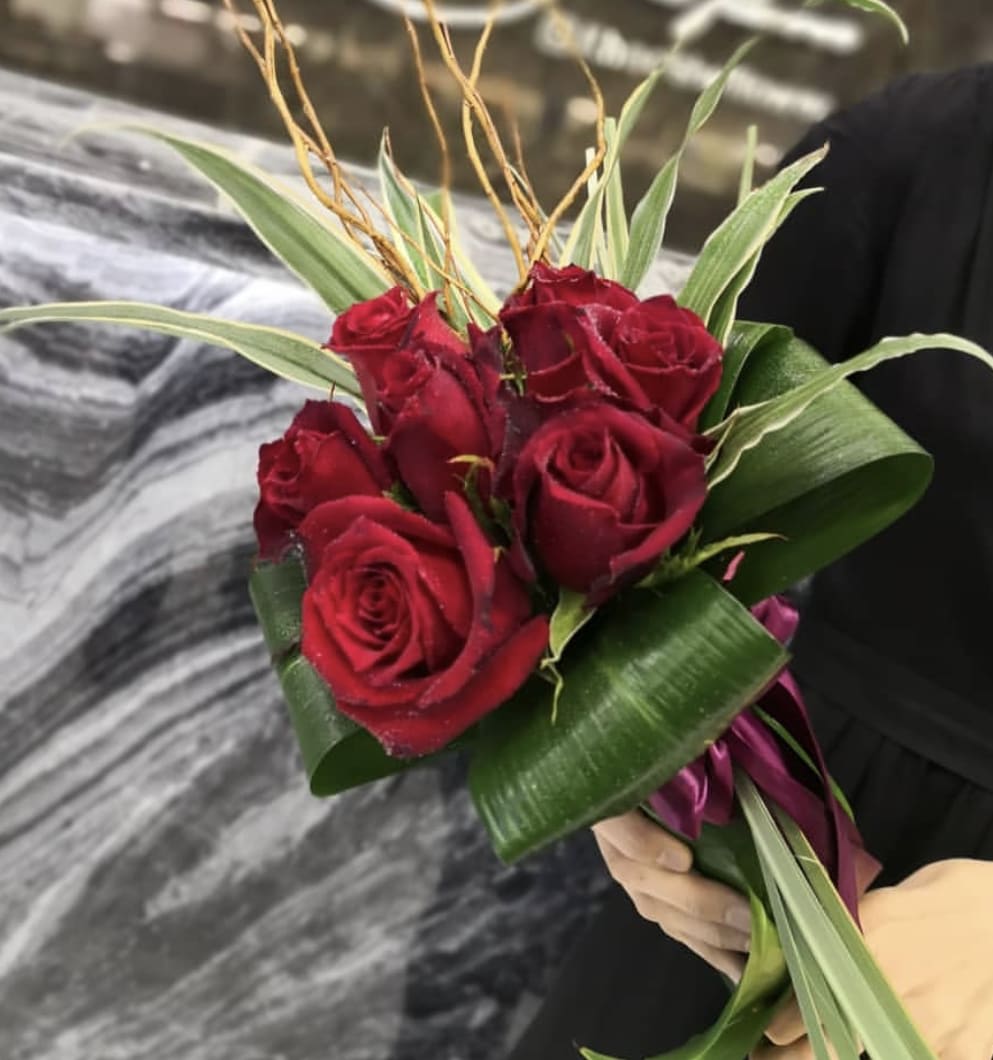 Hand Tied with Love - Eight Crimson Roses tied together with exotic leaves and curly willow. 