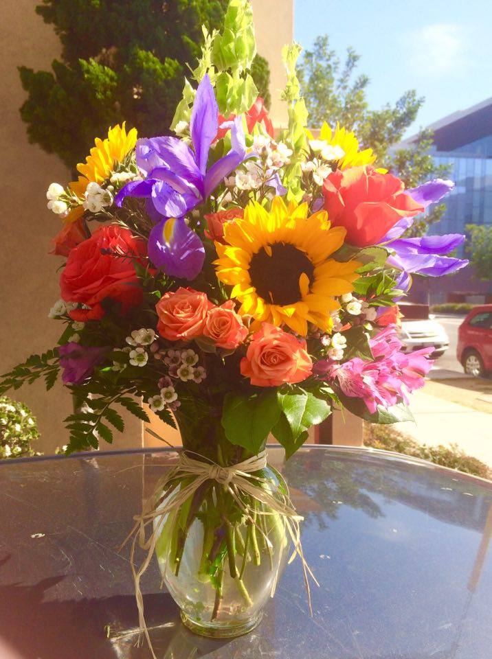 My Home Garden - My home garden is a perfect way to show your love. It combines some of our favorite flowers in a large clear glass vase tied with raffia. Deluxe version shown.