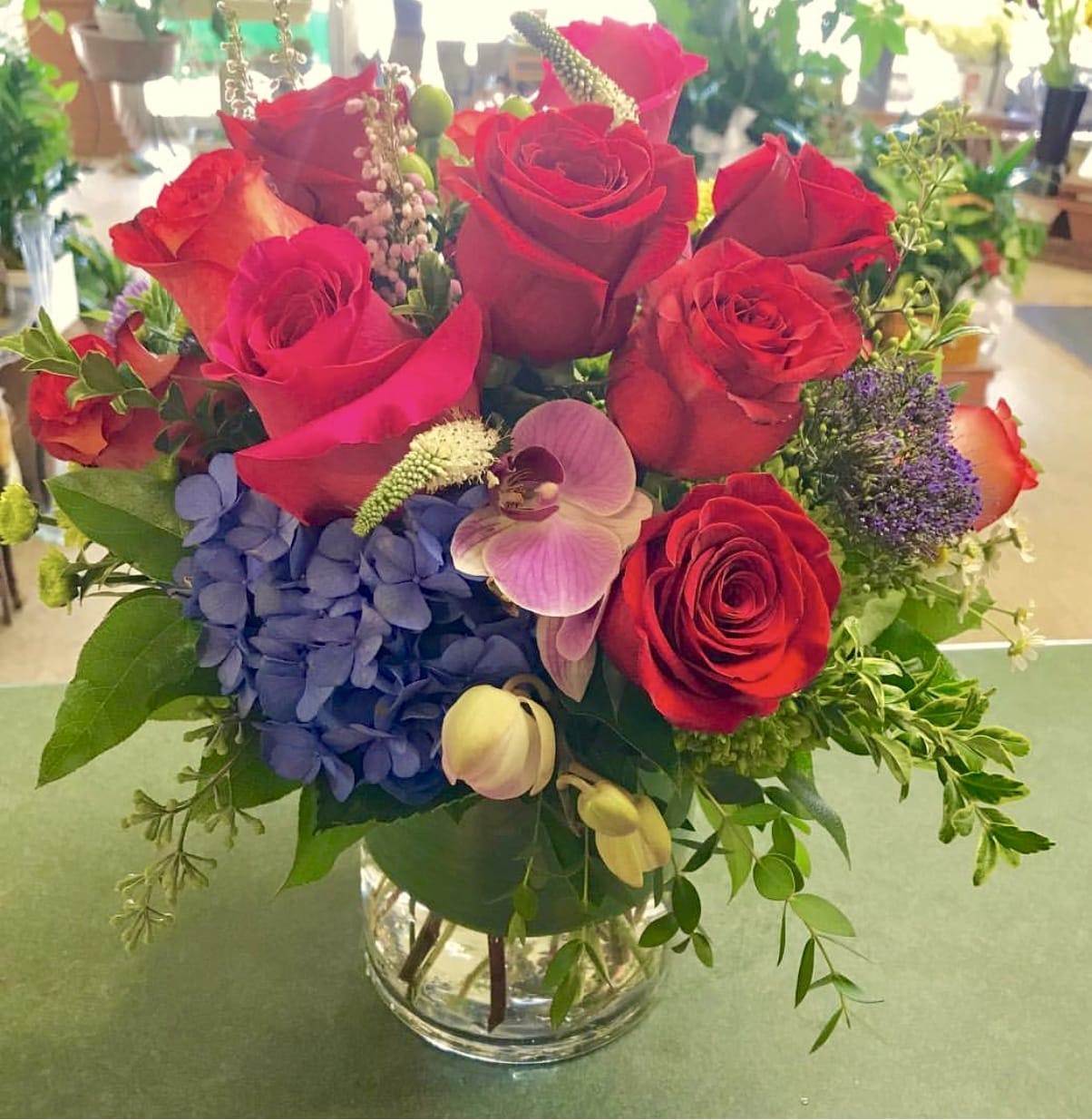 Sweet fire Sweet fire - Premium red roses in a cylinder vase accented by hydrangea and orchids.