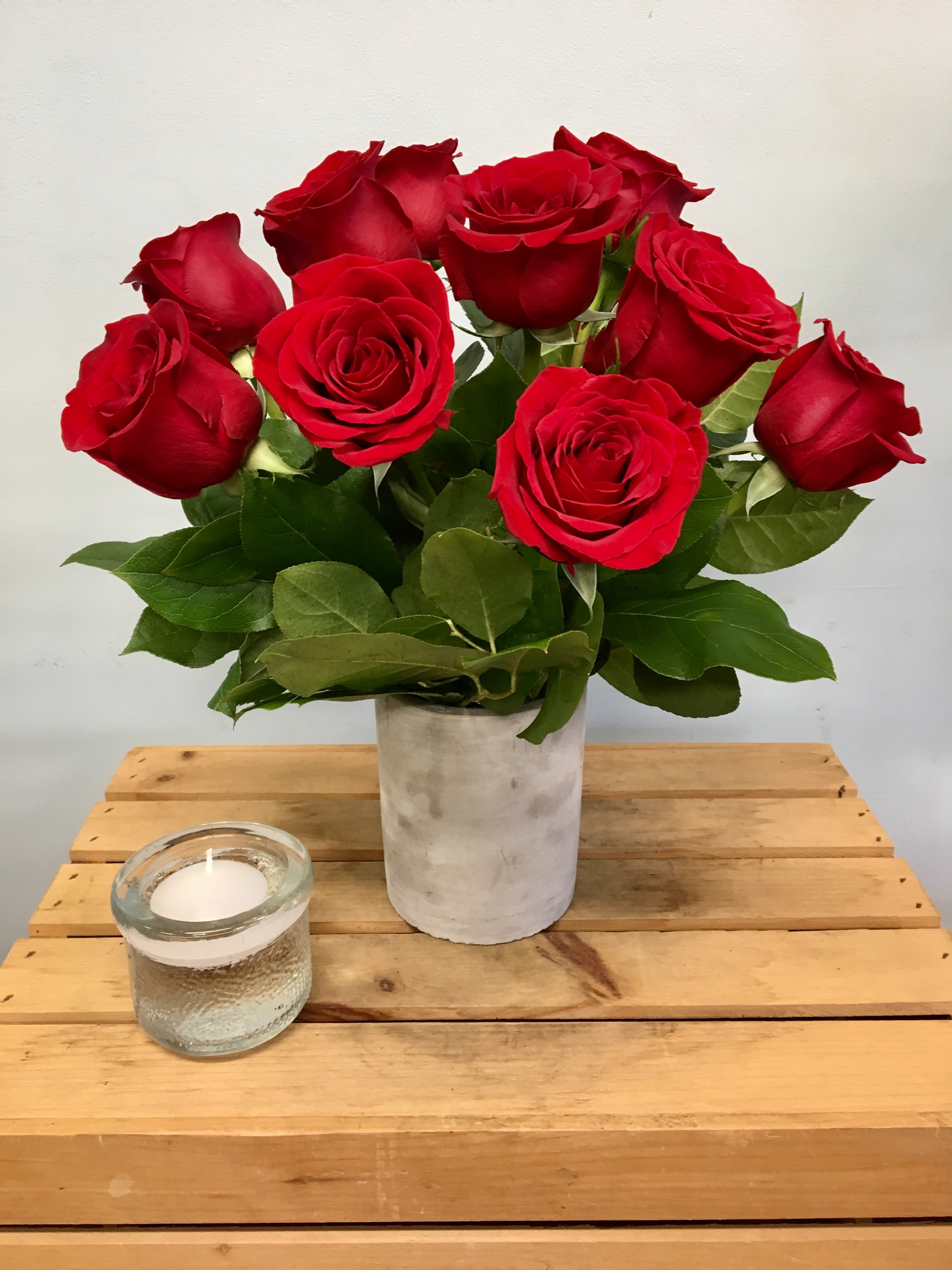 Natural Beauty Roses in Stone Vase - Lower Arrangement, measures Approx. 13&quot;h X 13&quot;w standard size (pictured) STANDARD=1 Dozen, DELUXE=18 Roses, PREMIUM=2 Dozen Keep it simple and natural with rich red roses arranged in a short stone cylinder surrounded by lush greenery.