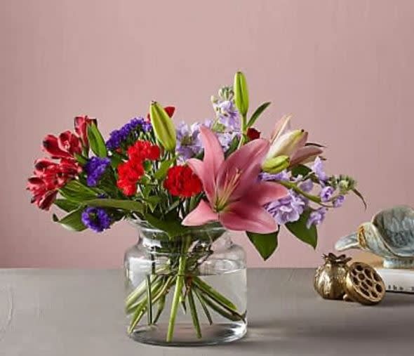 Romantique Bouquet - This fresh take on the classic Valentine's Day arrangement is just the bouquet to have your special someone swooning. Full blooms like lilies and roses take center stage in our Romantique Bouquet, while bold purple statice and dainty lavender stock spill out to add a bit of drama.