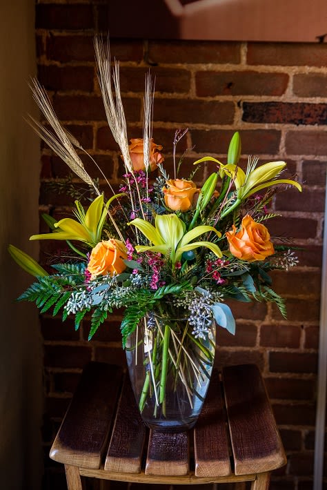 Lily Delight - This large vased arrangement showcases beautiful fall colored roses and lilies with a touch of wheat. 