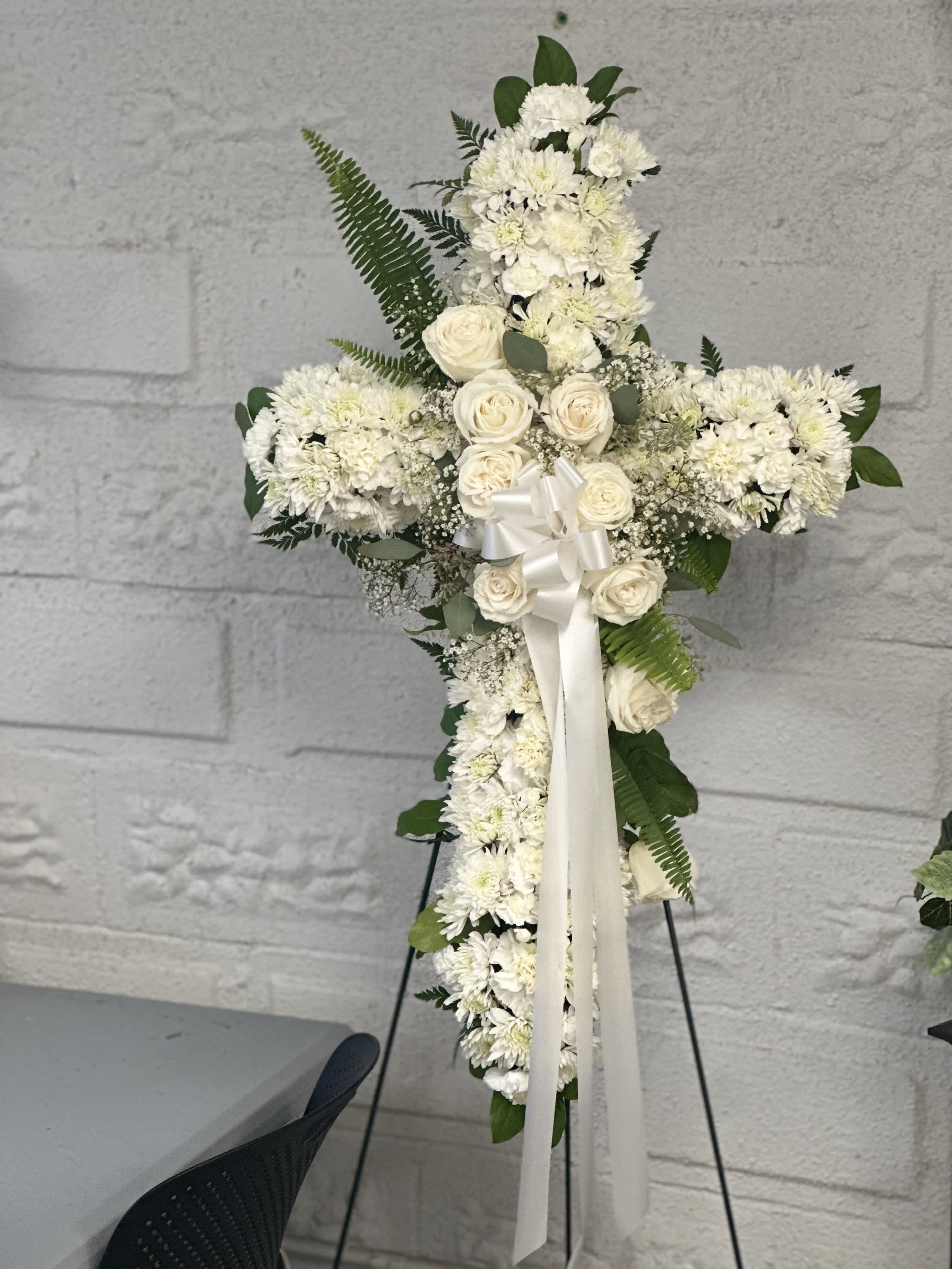 Eternal Peace Cross - Crafted with pristine white roses and chrysanthemums, symbolizing purity and tranquility, and accented with lush green plants, this standing cross arrangement offers solace and comfort during times of loss. A timeless expression of faith and love, it serves as a beautiful tribute to celebrate the life and legacy of your cherished one.
