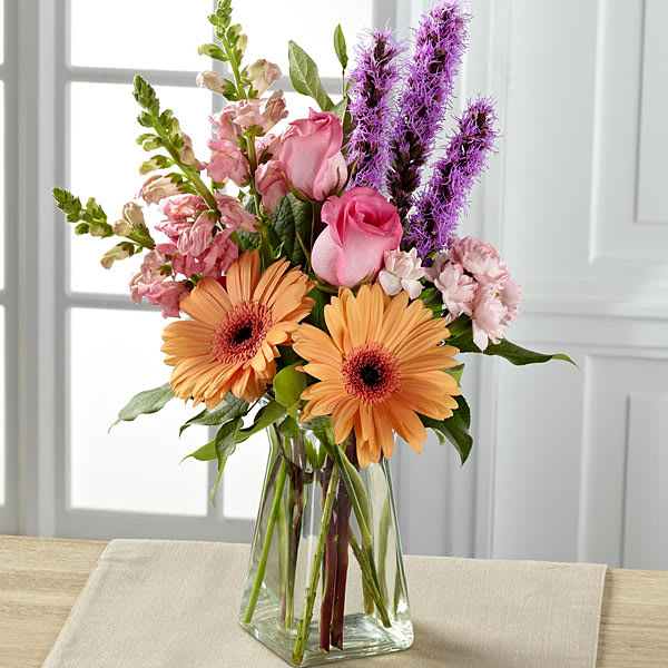  Blushing Invitations Bouquet - Exuding a special charm with a casual fresh-from-the-garden look this gorgeous spring bouquet is the perfect way to delight your recipient in honor of any of life's most treasured moments. Peach gerbera daisies are soft and sophisticated surrounded by pink roses pink snapdragons pink mini carnations purple liatris and lush greens arranged with an artist's eye in a gathered square clear glass vase. A wonderful way to celebrate a spring birthday Mother's Day or to express your thanks and gratitude. GOOD bouquet includes 12 stems. Approx. 16&quot;H x 7&quot;W. BETTER bouquet includes 15 stems. Approx. 18&quot;H x 8&quot;W. BEST bouquet includes 18 stems. Approx. 23&quot;H x 10&quot;W.