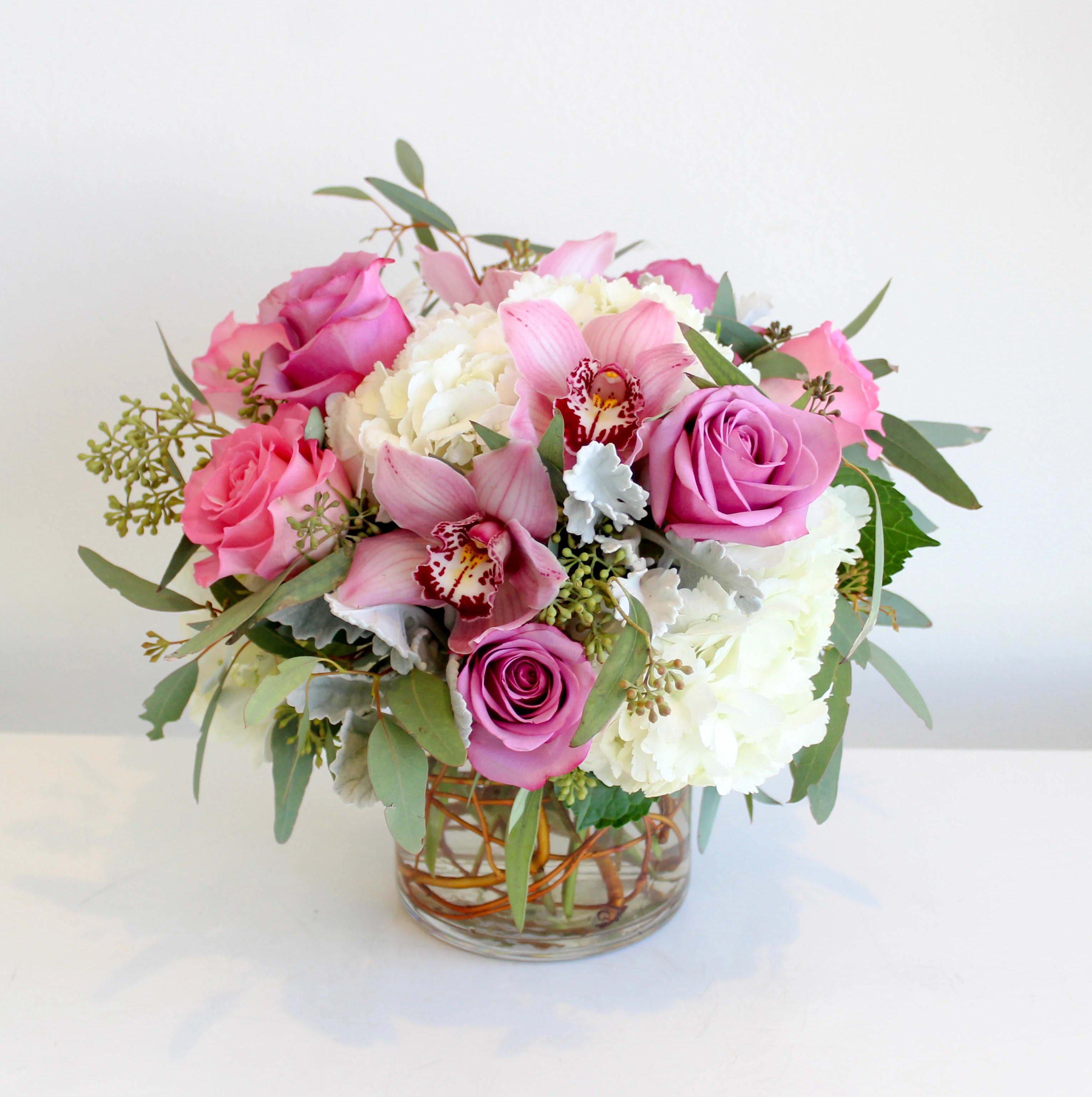 Pretty Please   - This stunning bouquet features a delightful blend of roses, orchids, hydrangeas, and seeded eucalyptus. The combination of these flowers creates a harmonious arrangement that is sure to bring joy to anyone who beholds it. The dimensions of this lovely bouquet are approximately 10.5 inches by 10.5 inches.