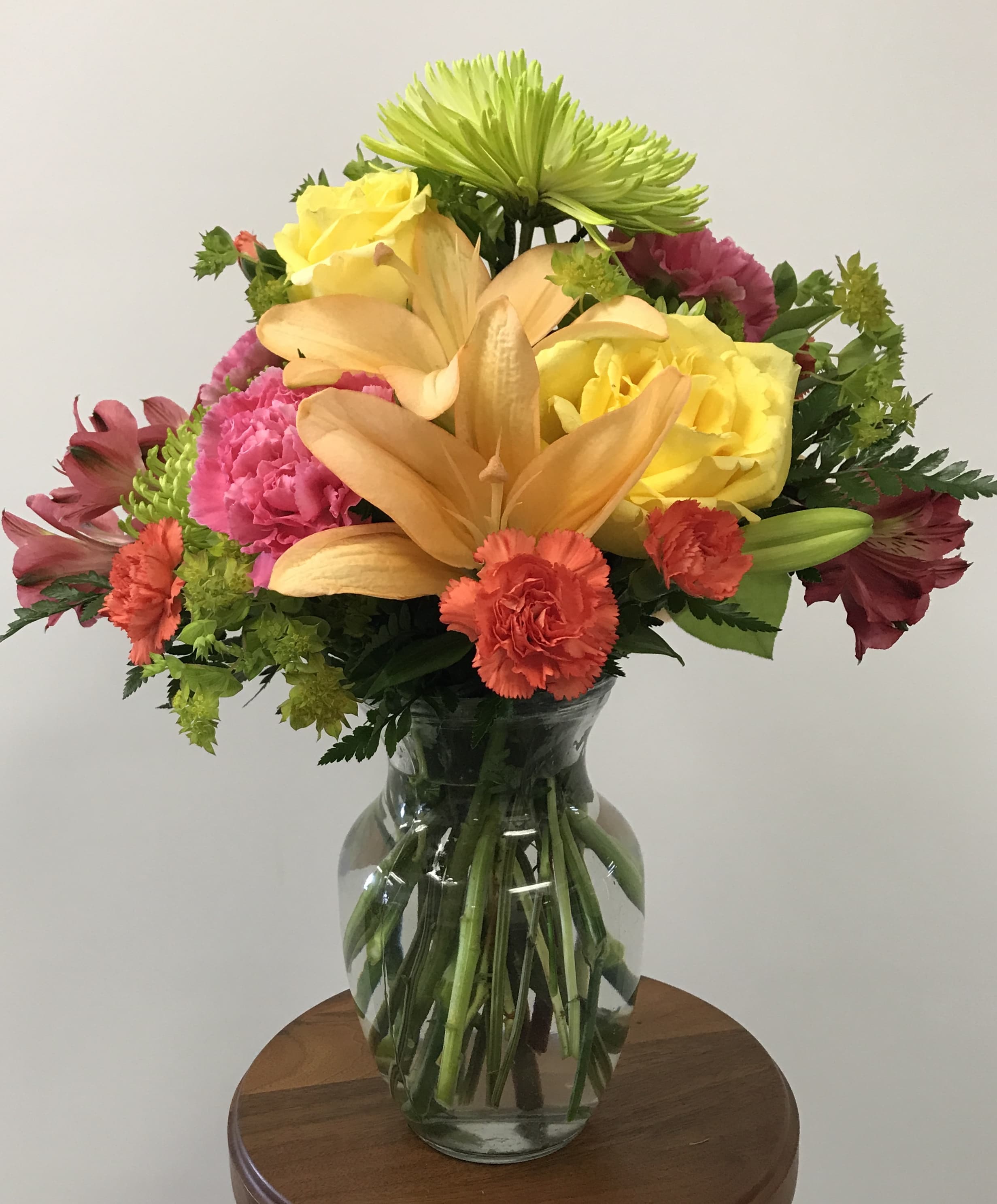End of the Rainbow - Hot fun in the summertime is here, and it's flowerific to be sure! This beautiful bouquet brings together a rainbow of the season's brightest blossoms. Hot pinks, oranges, greens and yellows are delivered in a charming glass vase.  It is sure to brighten someone's day. 
