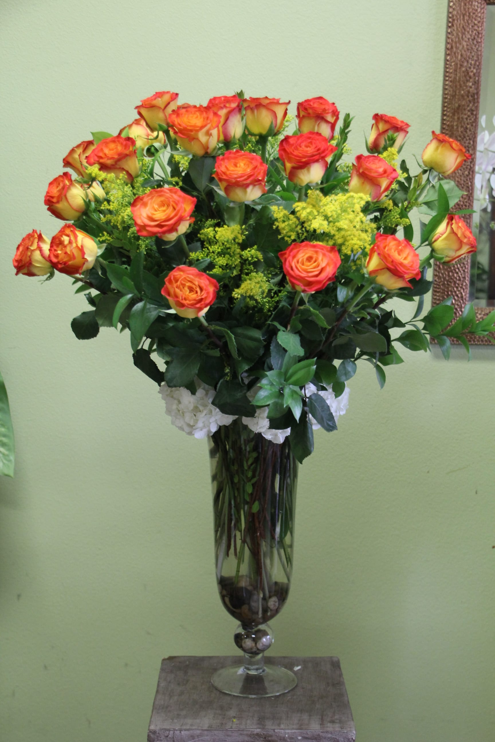 Two dozen long stem High Magic Two-Toned Yellow n' Orange Roses - These High Magic Roses are among the most unique in the two-toned family. And with this elegant crystal vase and stones placed inside, this arrangement is sure to leave a lasting impression. 