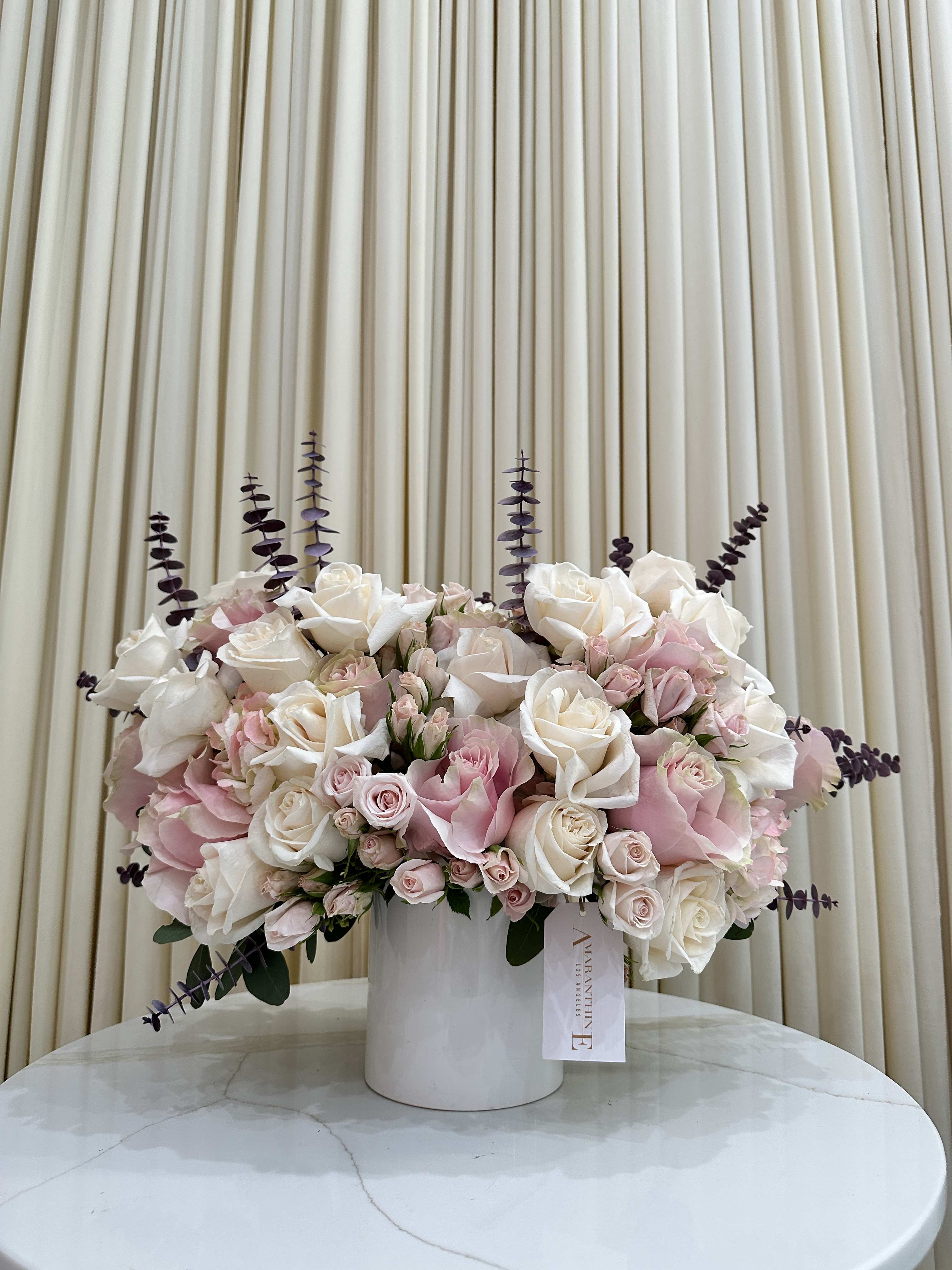 Blush &amp; Bloom - Bathed in Sunlight, Kissed by Pink: A Whisper of Spring in Every Bloom Imagine a gentle melody of color, a dance of delicate pinks and pristine whites nestled in a sun-kissed embrace. This isn't just a bouquet, it's a whisper of spring, a breath of fresh air for your home.  Blooms that Sing:  Petals soft as silk, bursting with the gentle hues of a blushing sunrise. Each bloom a masterpiece, whispering stories of budding hope and the playful grace of a butterfly's wings. Dancing in a symphony of textures, fluffy peonies mingle with dainty daisies, their fragrance a whispered love song filling the air. Sunlight's Warmth:  Nestled in a vase like a ray of captured light, the arrangement glows with a gentle radiance. Every curve reflects the sun's caress, casting playful shadows and painting your space with warmth. More than just a centerpiece, it becomes a beacon of joy, a silent invitation to slow down and savor life's simple pleasures. Beyond the Moment:  These blooms, though fleeting, leave a lasting impression. Let their vibrant whisper linger, transforming your space into a haven of serenity. Share their gentle beauty, a perfect gift for a loved one, a vibrant touch for a celebration, or a moment of mindfulness for yourself. Bathed in Sunlight, Kissed by Pink is more than just an arrangement, it's a feeling. It's the warmth of a spring breeze on your skin, the hushed sweetness of nature's perfume, and the delicate reminder that beauty, like a flower, unfolds in every moment.  Bring this whispered spring into your home. Order your bouquet today and let the petals sing.  