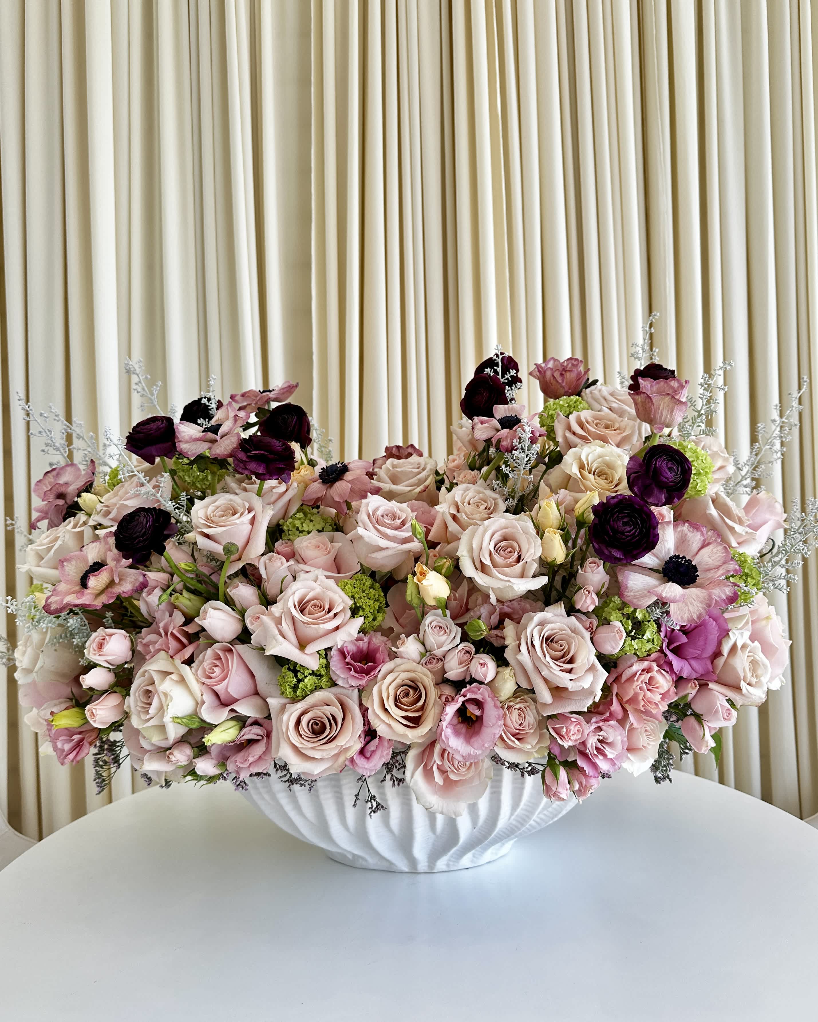 Elegant Harmony - Embrace the &quot;Elegant Harmony&quot; Floral Vase, a perfect fusion of beauty and grace. Delicate shades of light pinks, deep purple, and lush greens come together in this stunning arrangement, lovingly placed in a pristine white vase. Elevate your space with the timeless charm of these exquisite florals, adding a touch of elegance and serenity to any setting. Whether it's a centerpiece for a special occasion or a thoughtful gift for someone dear, &quot;Elegant Harmony&quot; is sure to leave a lasting impression of natural beauty and tranquility. 