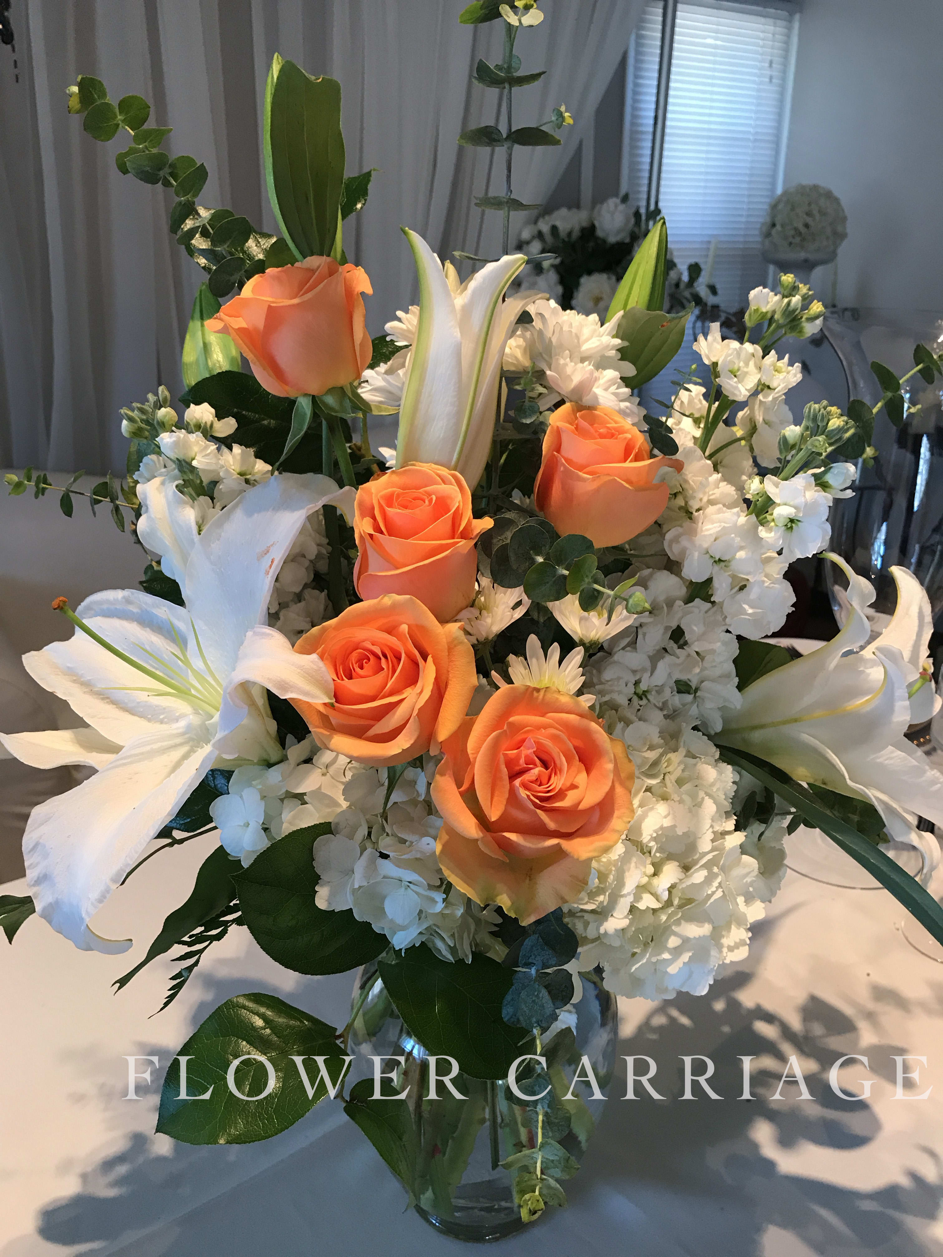 Peacefully Peach By Flower Carriage - Deliver a white bouquet with a splash of peach color to bright up the day. This arrangement features: roses, lilies, stock, hydrangea, chrysanthemums, and eucalyptus.   