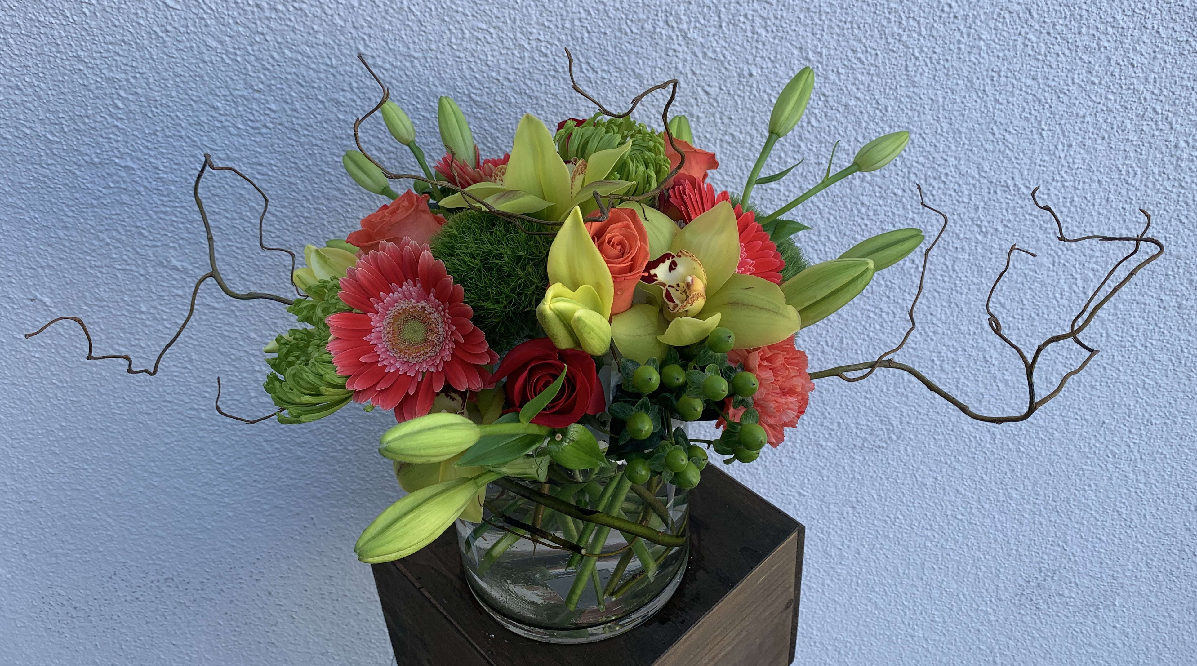 Summer Breeze - A refreshing arrangement of green cymbidium orchids, green spider mums, orange gerbera daisies, orange and red roses, and yellow lilies. 
