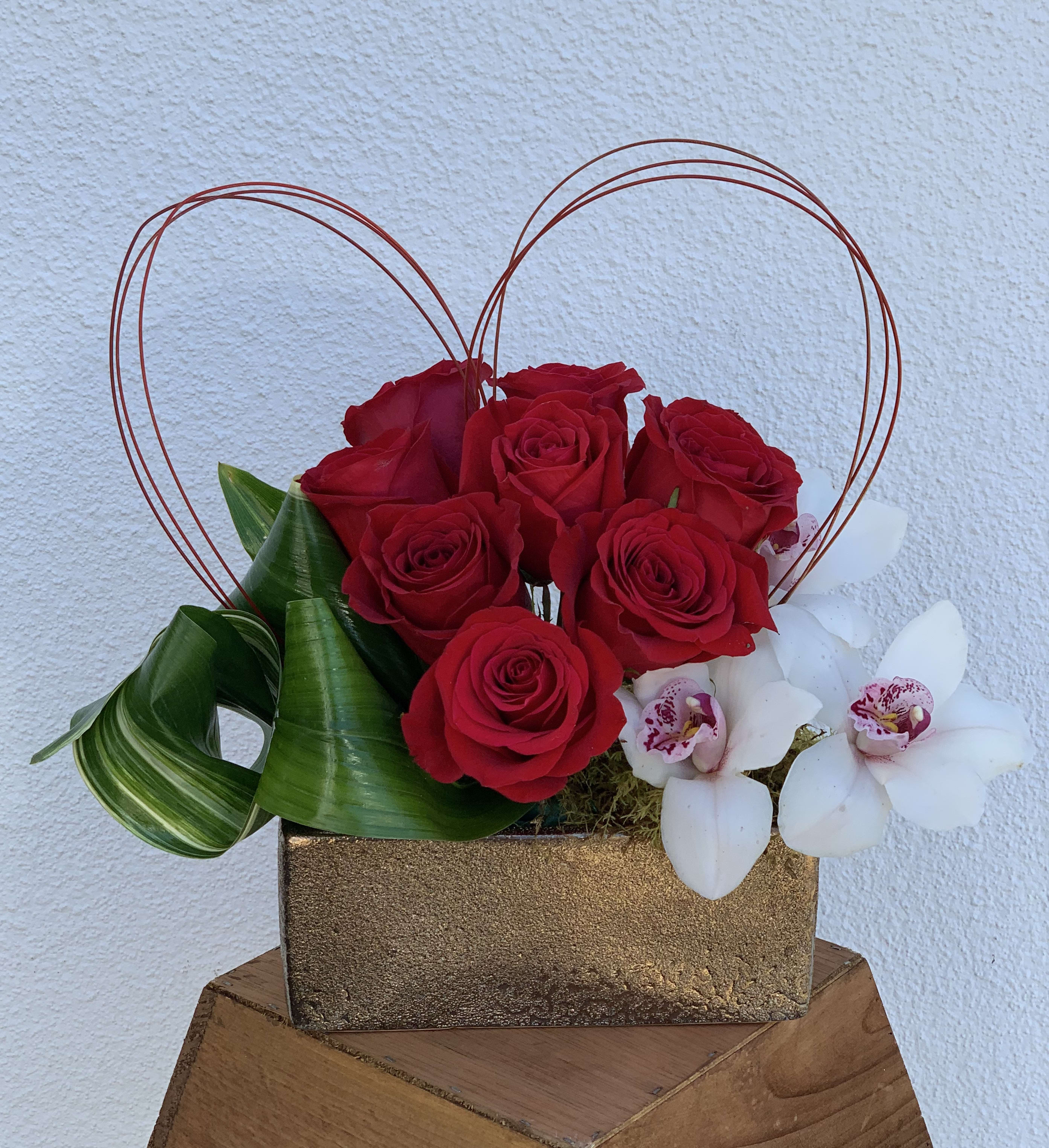 From the heart - A beautiful arrangement of red roses, cymbidium orchids, and aspidistra leaf in a ceramic vase.  This will surely show them how much you love them.  