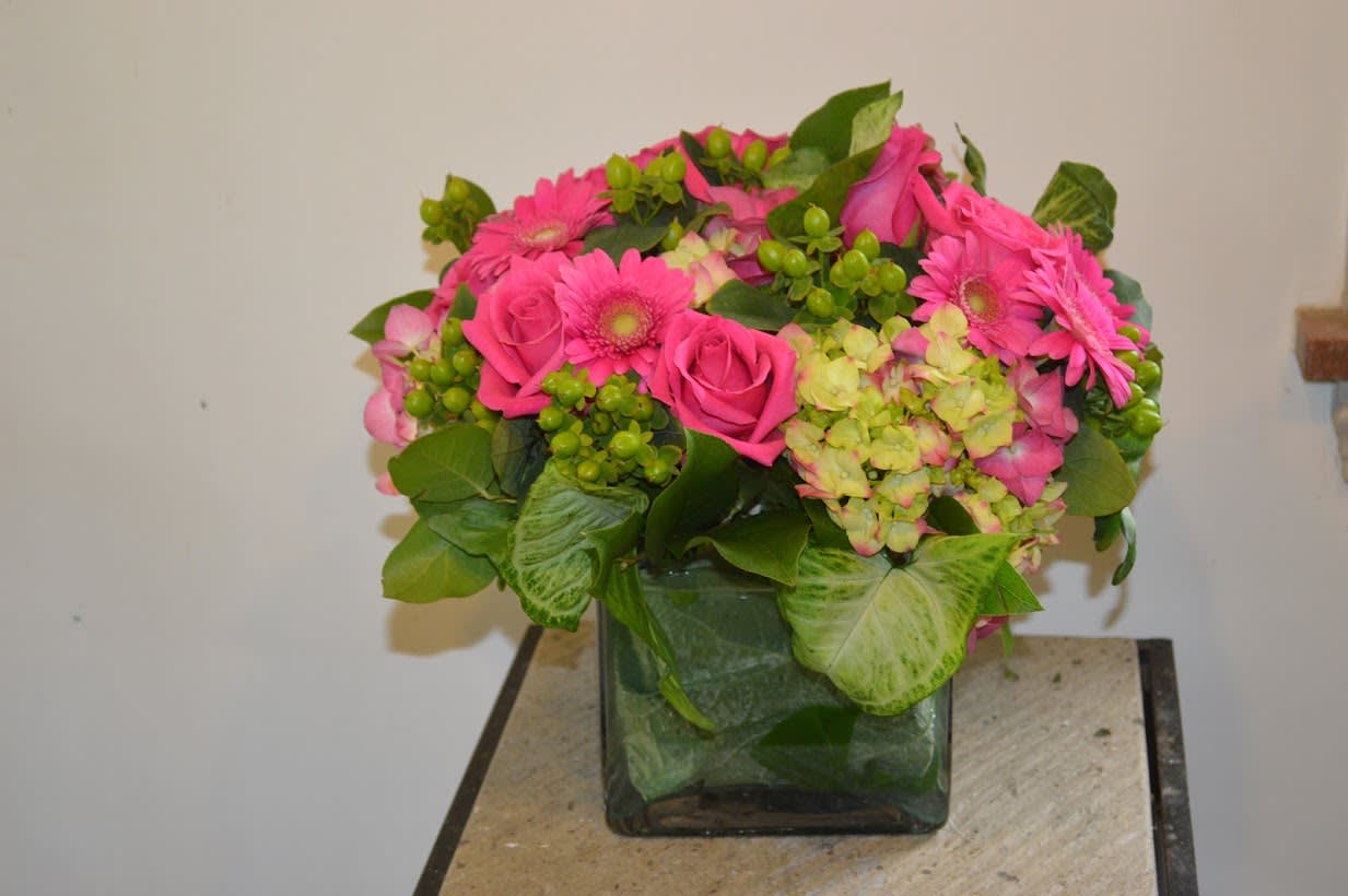 Pink Rose Arrangement - Pretty pink roses, pink gerbera daisies, little hypericum berries, hydrangea and a variety of greens. This arrangement was done very low and tight in a leaf wrapped square glass cube.