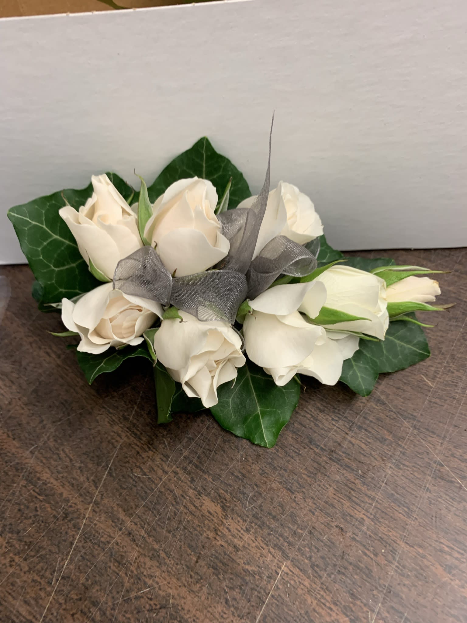 White Rose wrist corsage - Delicately crafted white spray rose, green Ivy leaves, A White ribbon completed the corsage. This corsage can be made  to pin on.  A different color ribbon can be used to match your attire  