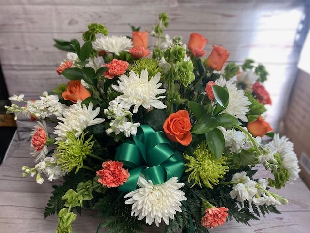 Irish Blessings Funeral Basket - A beautiful wicker basket in an Irish theme.  Bells of Ireland, Green fugi mums, white cremones, white stock, orange roses and orange carnations.
